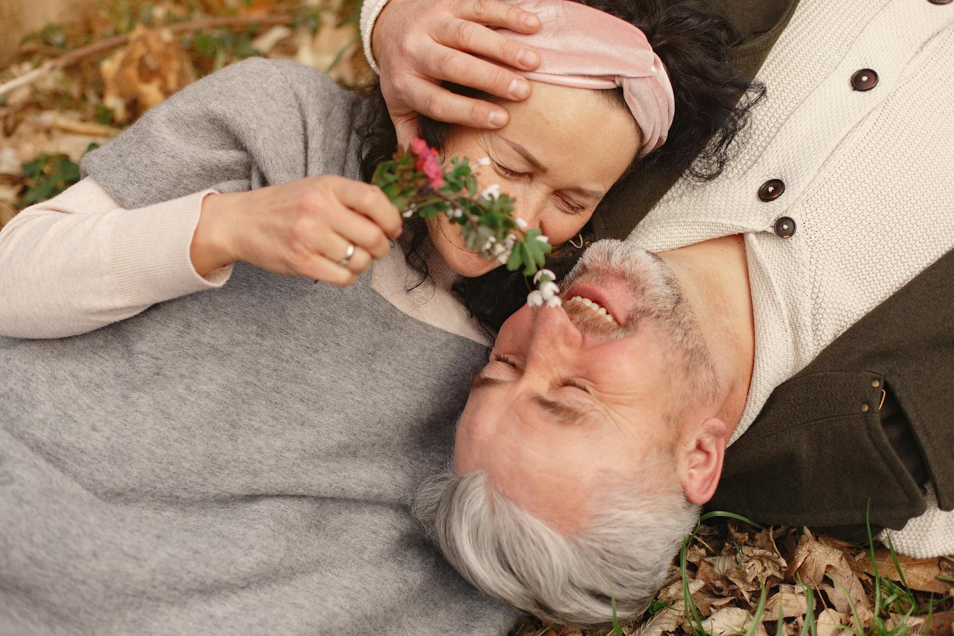 Una pareja de ancianos se acurruca tumbada sobre un montón de hojas caídas | Fuente: Pexels