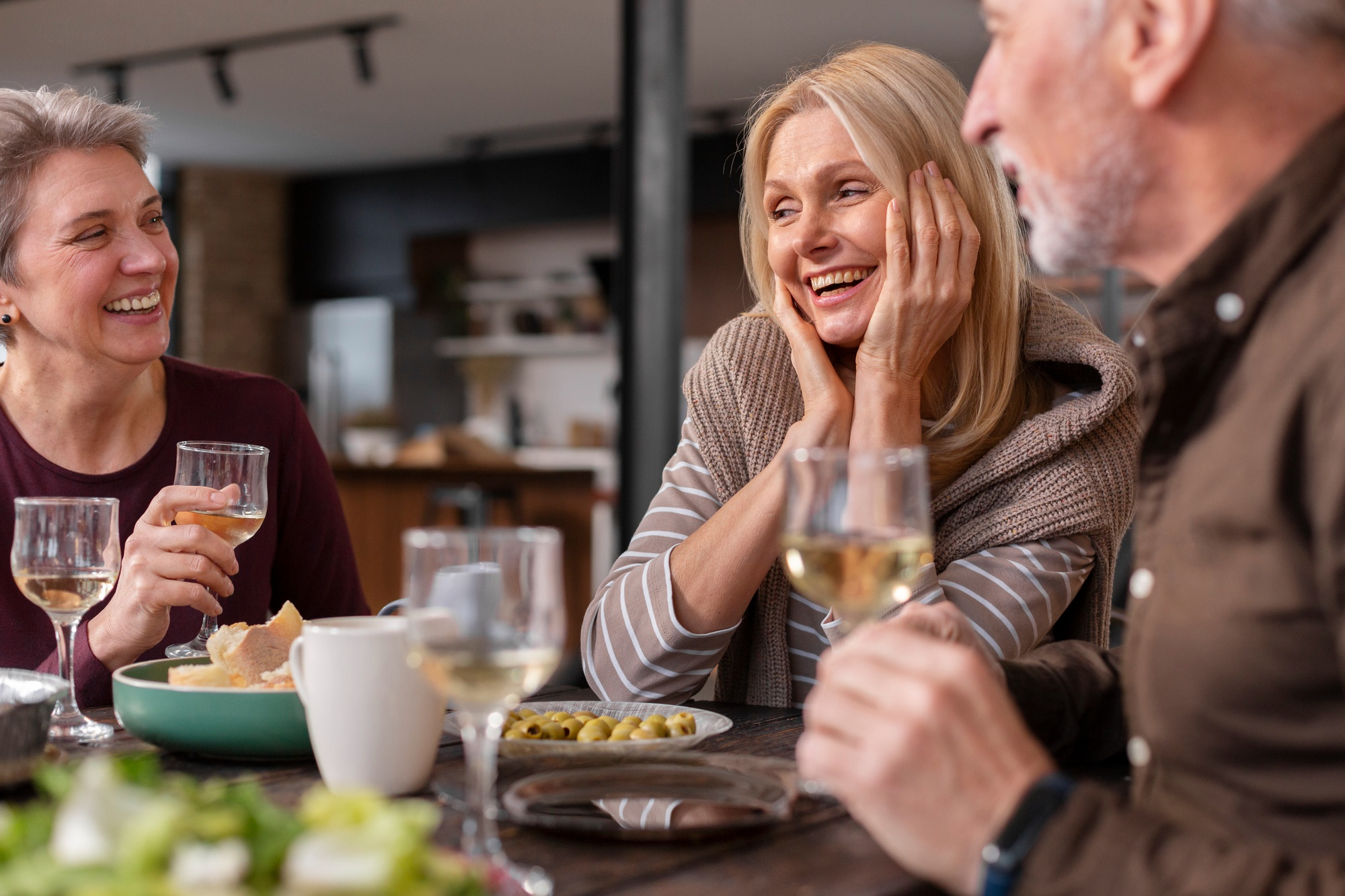 Una pareja feliz y una mujer brindando mientras disfrutan de una comida | Fuente: Freepik