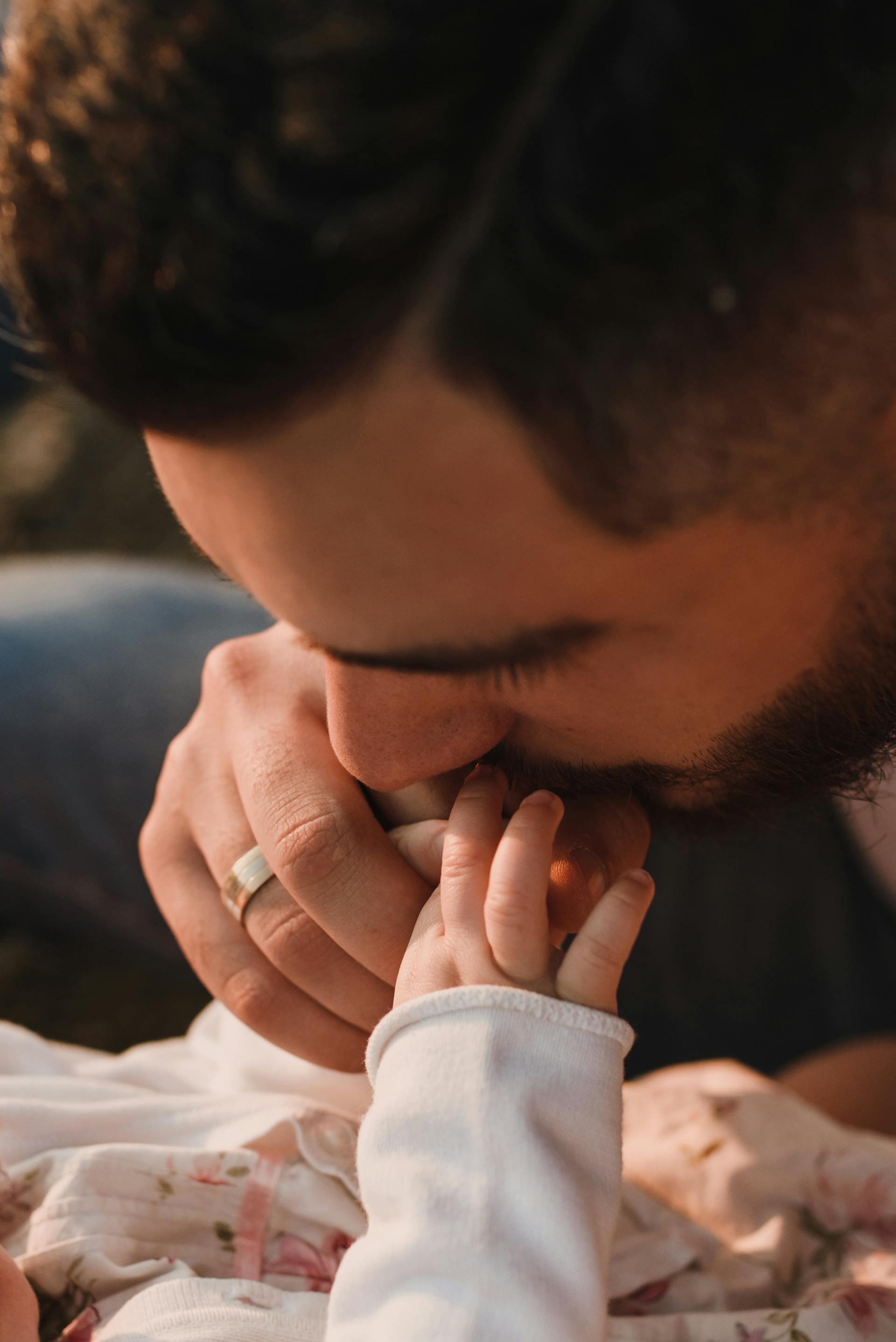 Un hombre besando la mano de un bebé | Fuente: Pexels