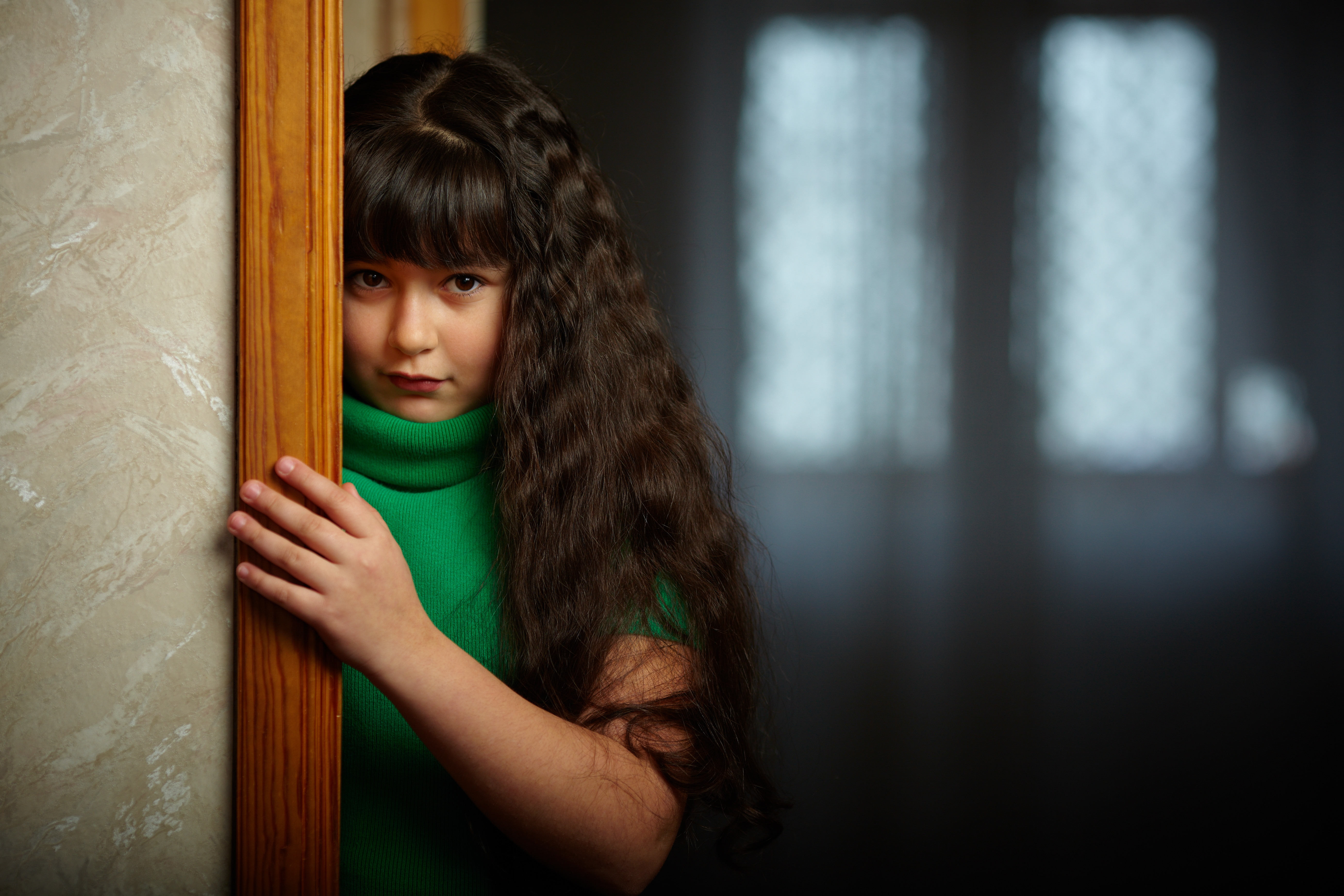 Chica triste cerca de la puerta | Fuente: Shutterstock.com