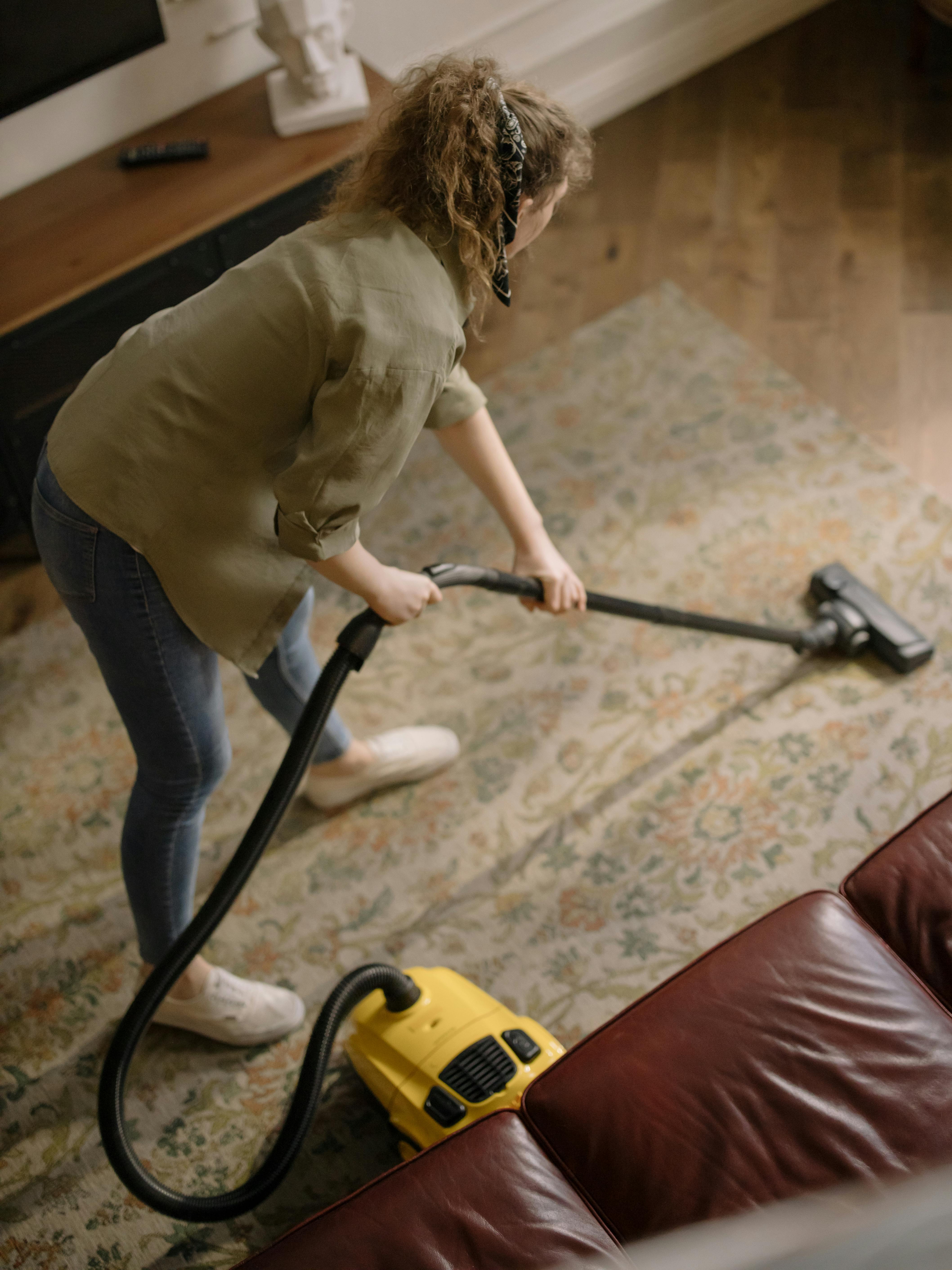 Una mujer usando una aspiradora en una alfombra | Fuente: Pexels