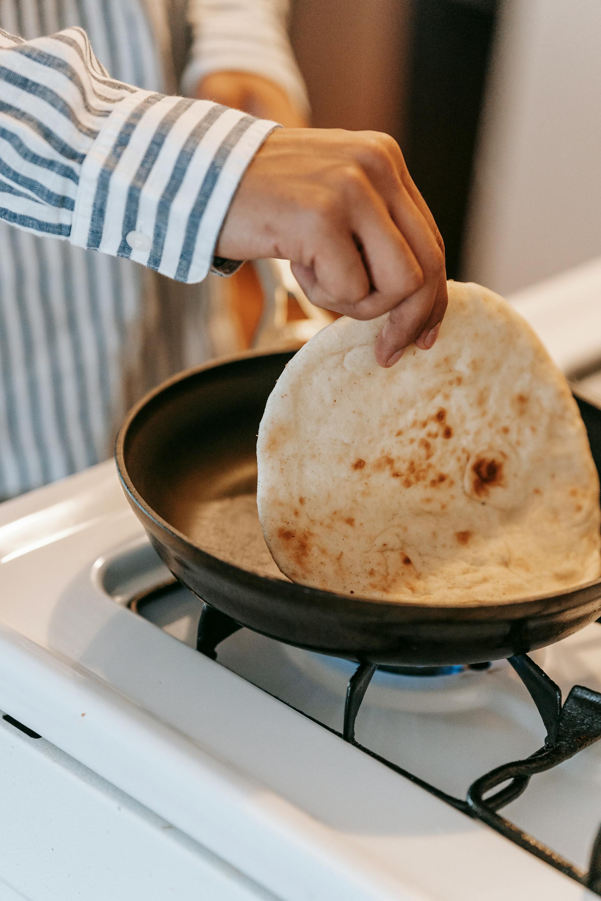 Un hombre haciendo pan plano en la cocina | Fuente: Pexels