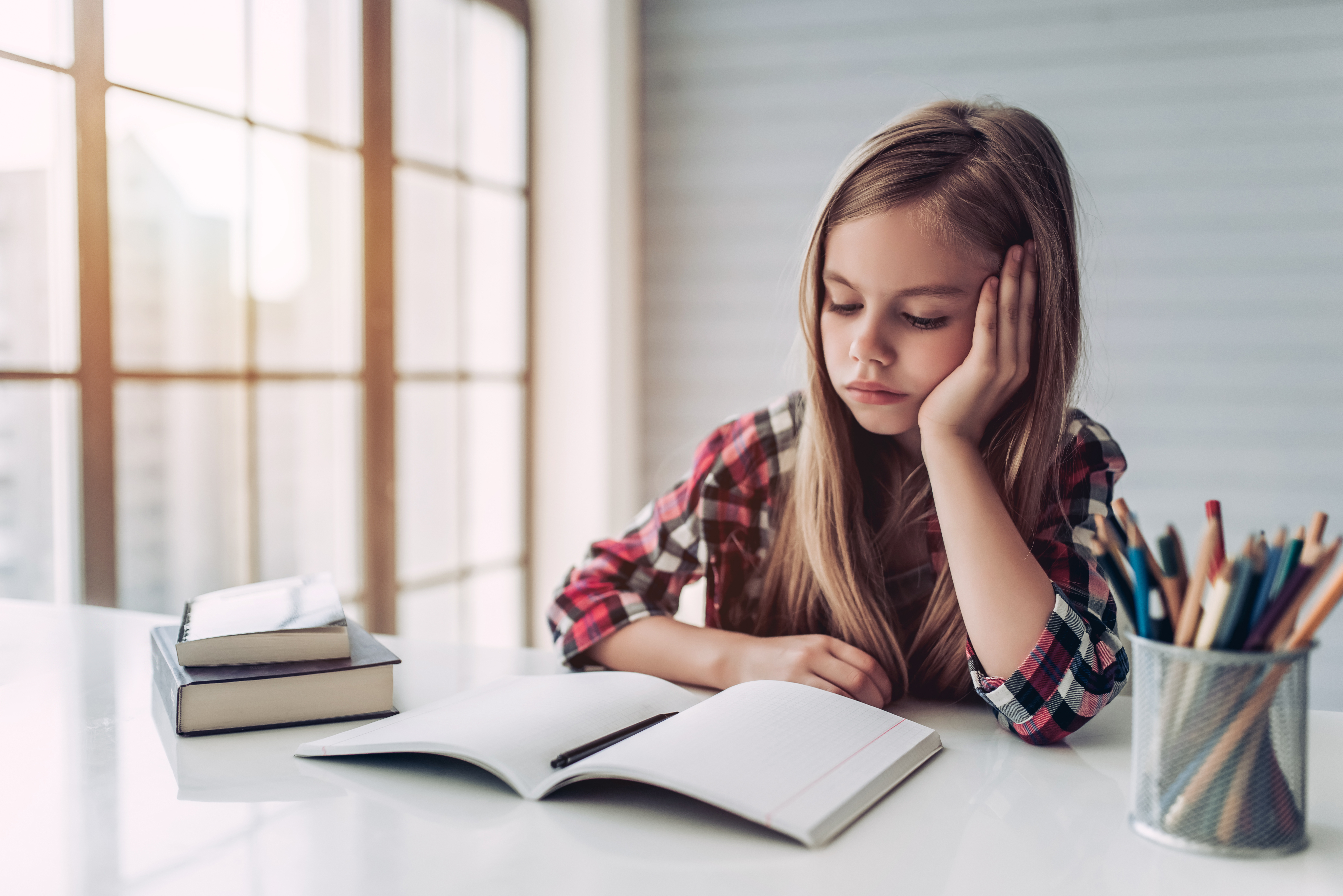 Una joven triste mirando un libro en su escritorio | Foto: Shutterstock