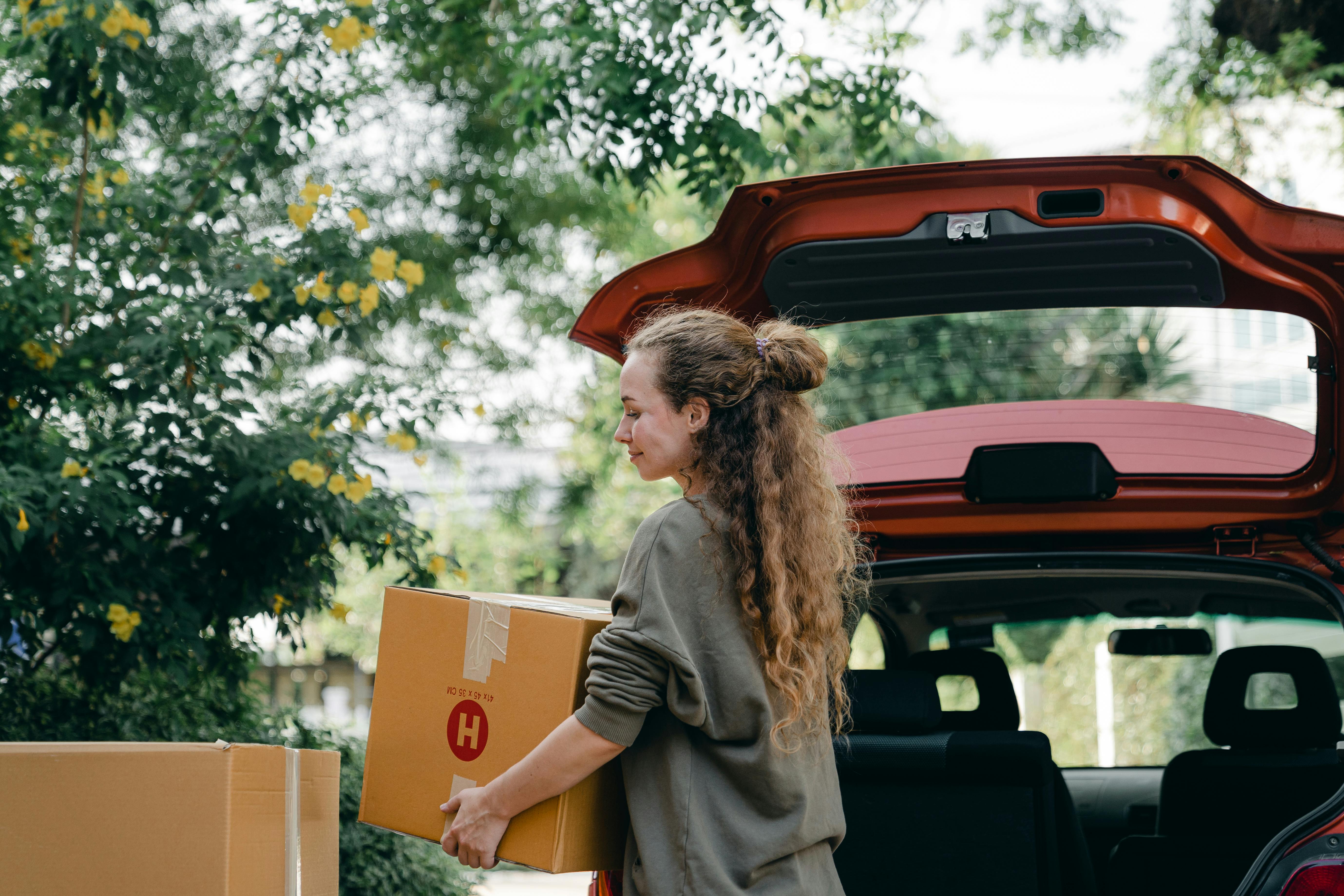 Una mujer feliz cargando cajas en su Automóvil | Fuente: Pexels