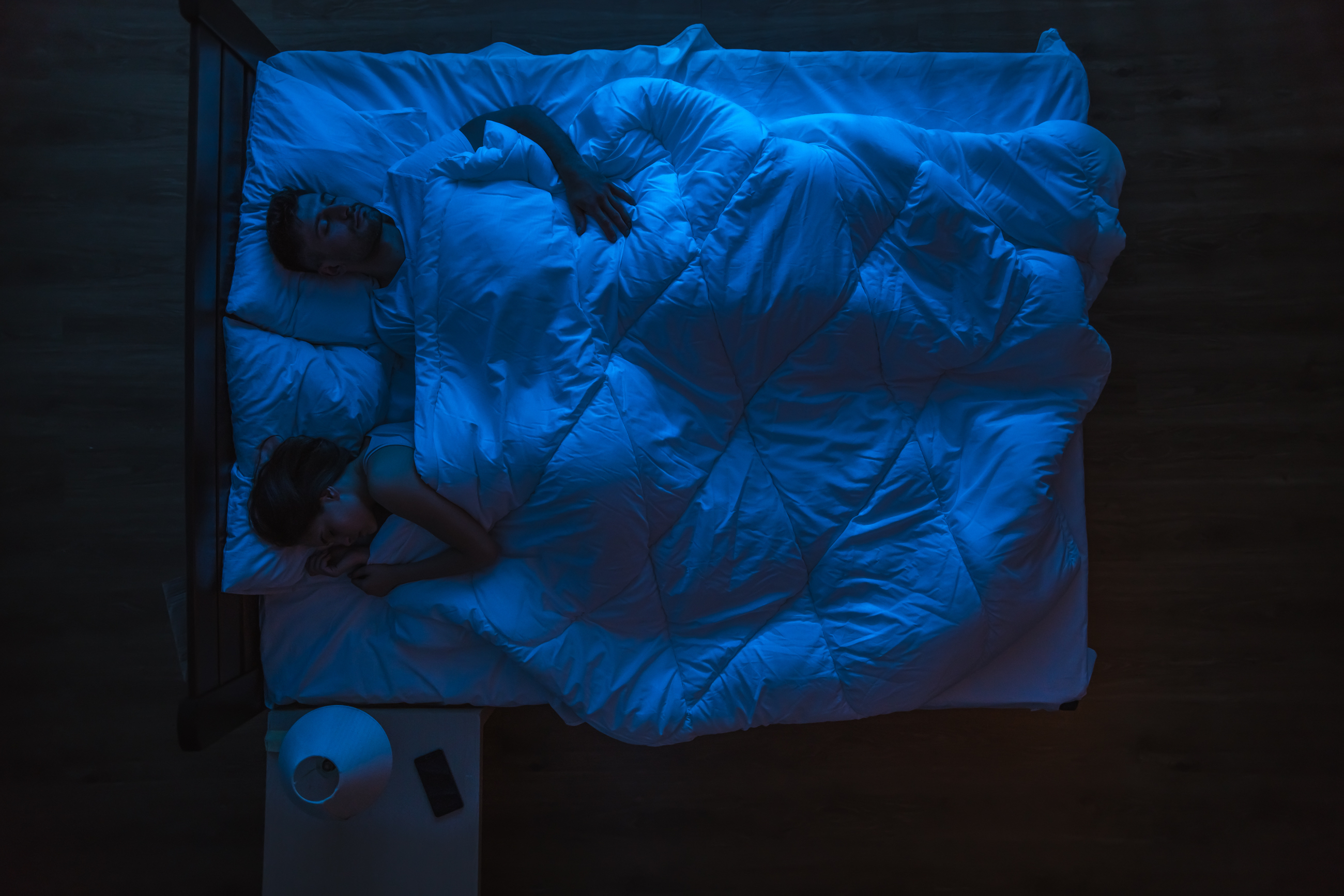 Pareja durmiendo en una cama. Tarde noche. | Fuente: Shutterstock