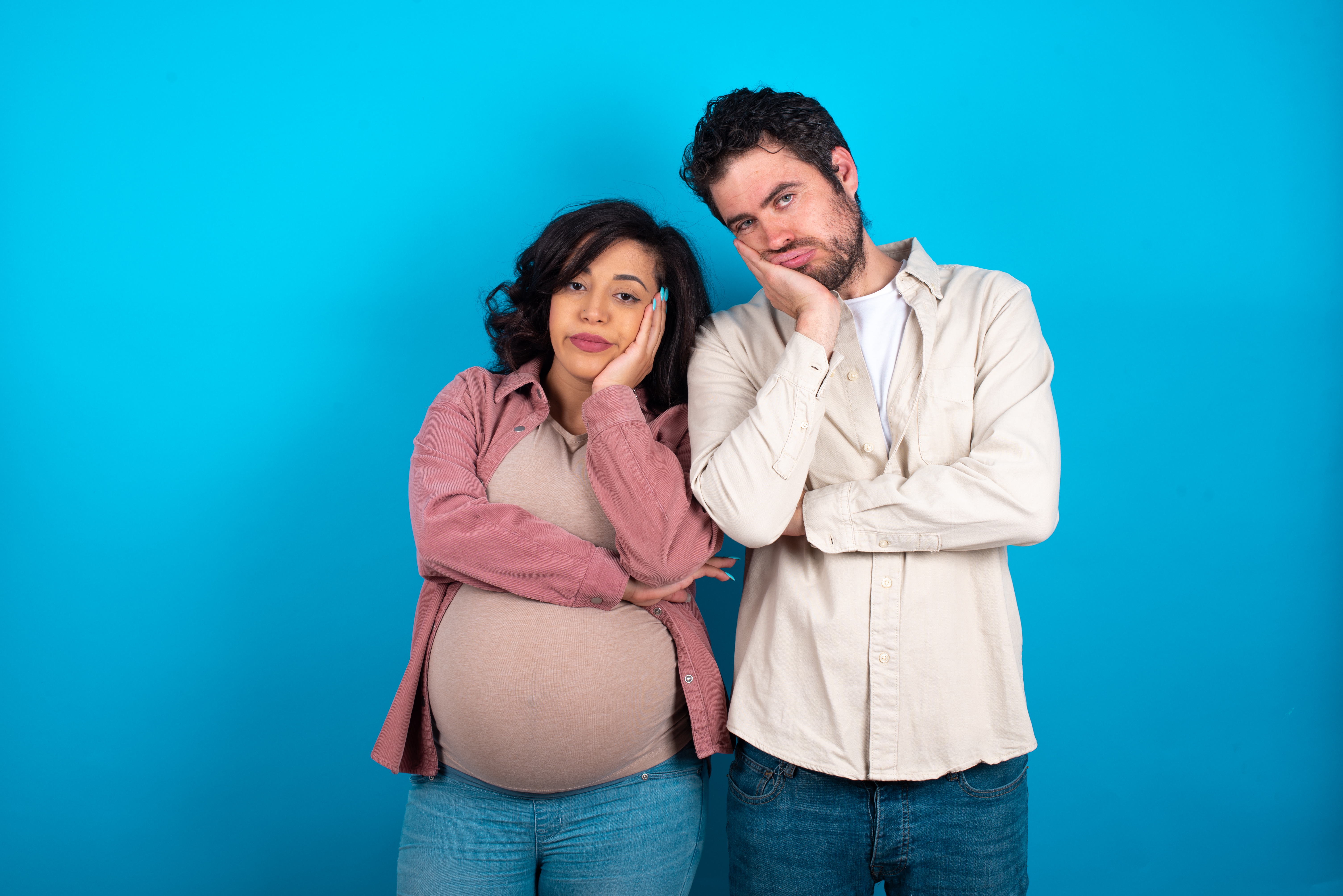 Una joven pareja que espera un bebé parece aburrida. | Foto: Shutterstock