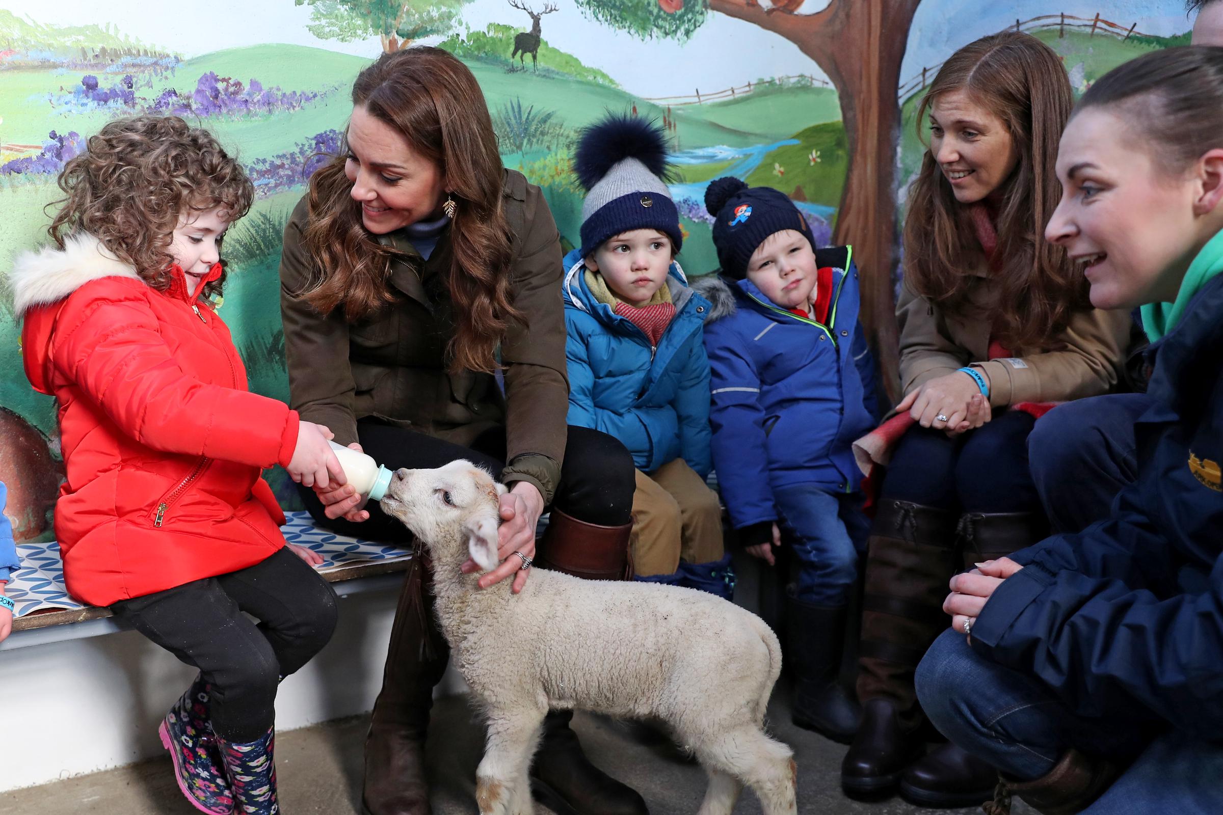 Catherine ayuda a alimentar a un cordero con niños de dos guarderías locales durante una visita a The Ark Open Farm el 12 de febrero de 2020, en Newtownards, Irlanda del Norte | Fuente: Getty Images