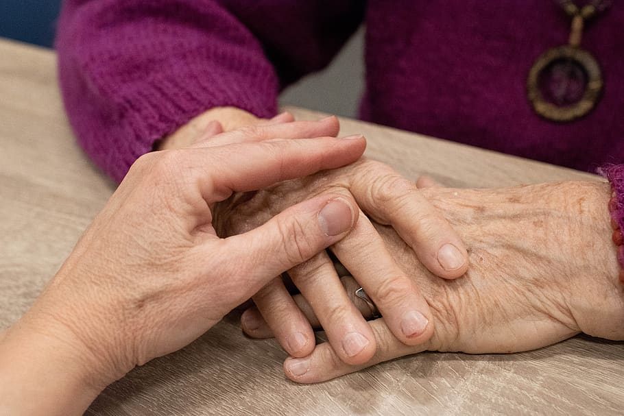 Persona tomando las manos de una anciana. | Foto: PxFuel