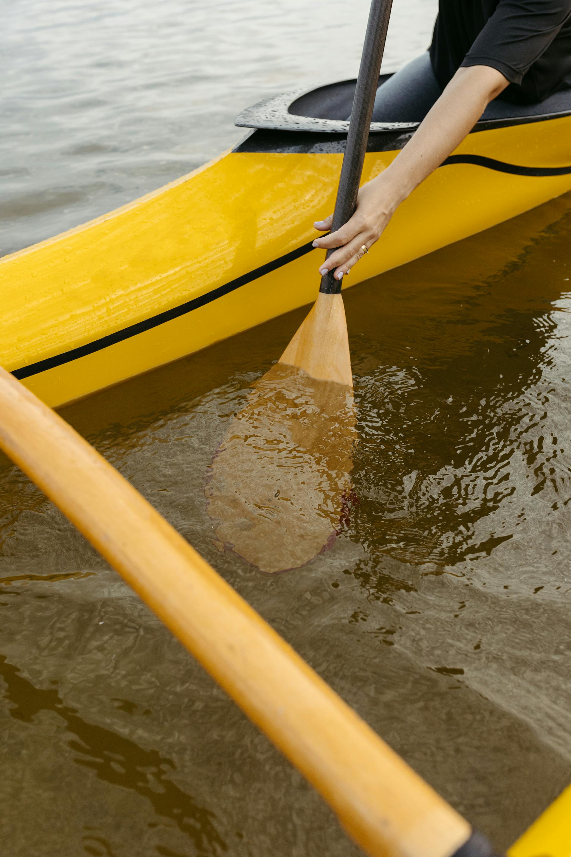 Primo piano di una persona che pagaia su una canoa gialla | Fonte: Pexels