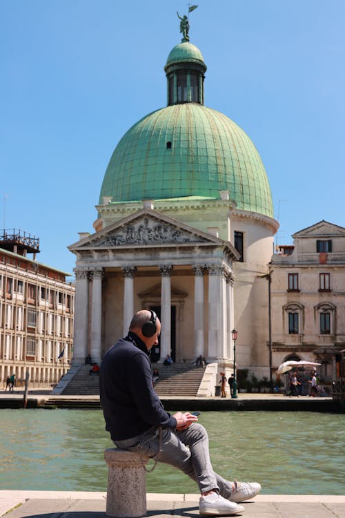 Un hombre sentado junto al canal | Fuente: Pexels