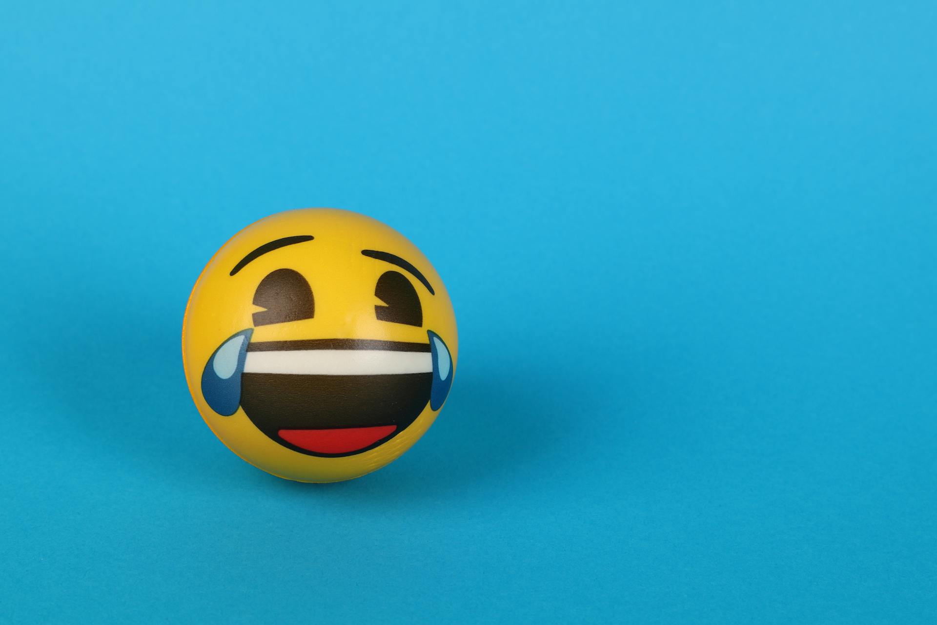 Un emoji riendo con lágrimas sobre una superficie azul | Fuente: Pexels