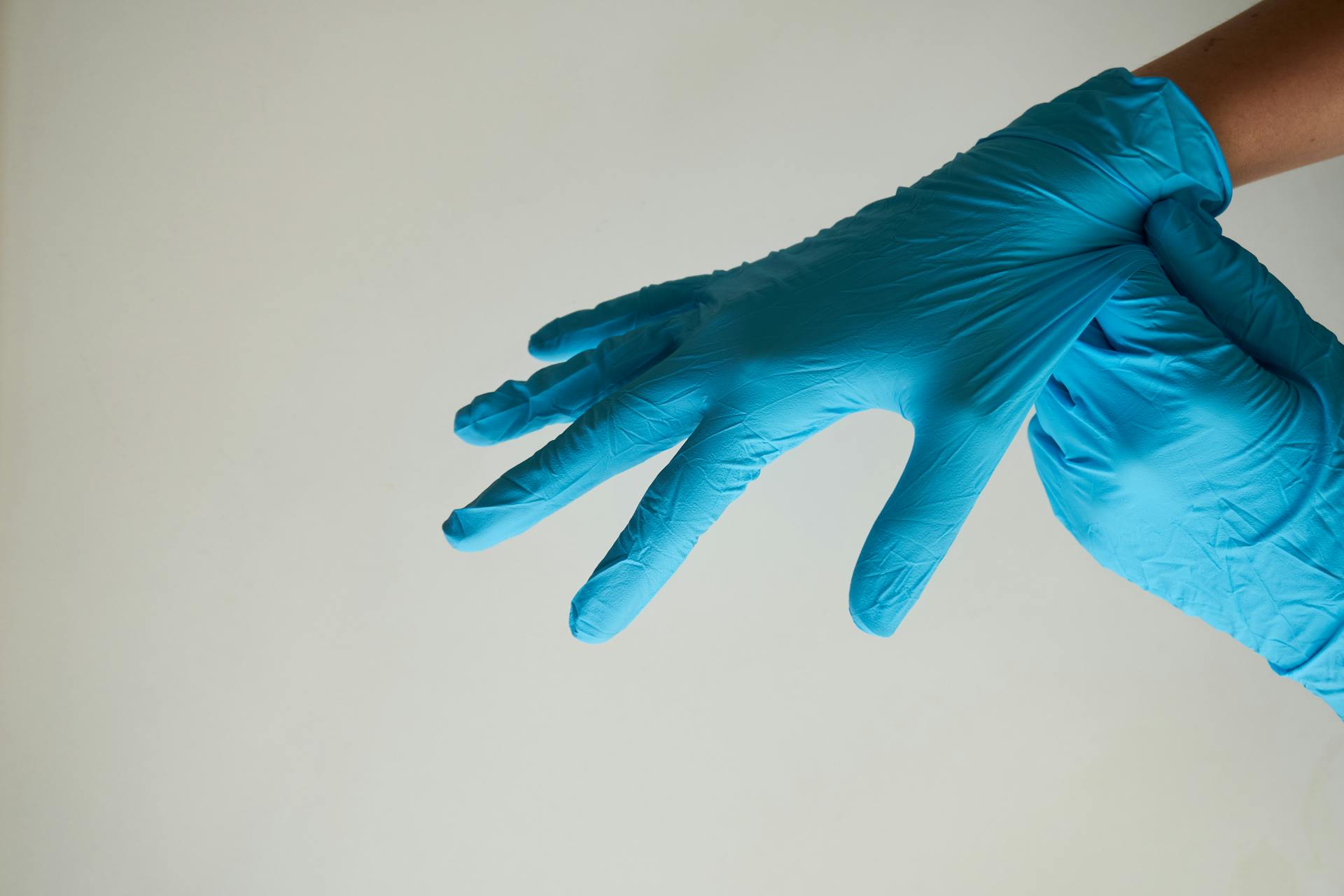 Una mujer poniéndose guantes de látex azul | Fuente: Pexels