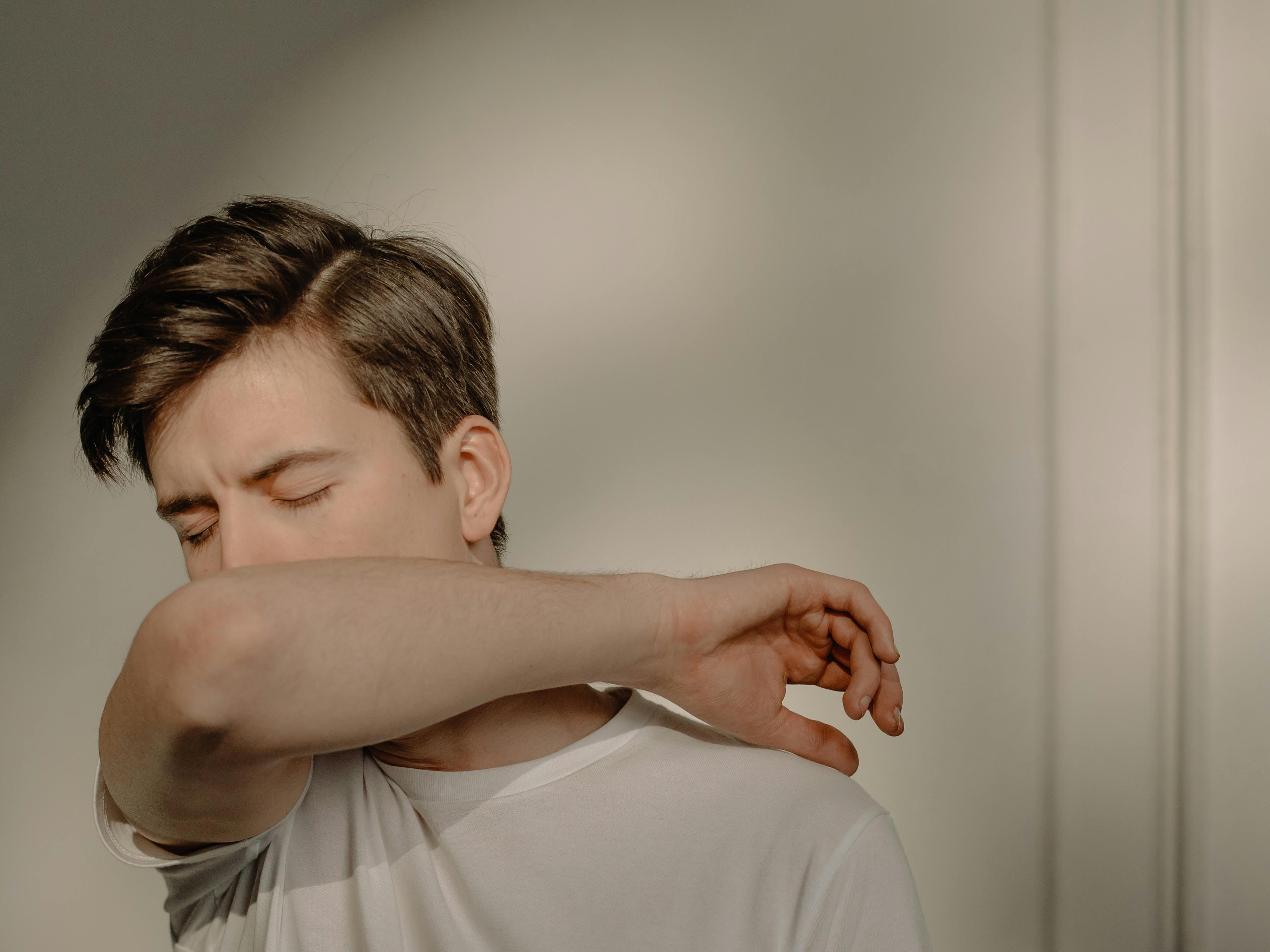 Un hombre tosiendo en su brazo | Fuente: Pexels