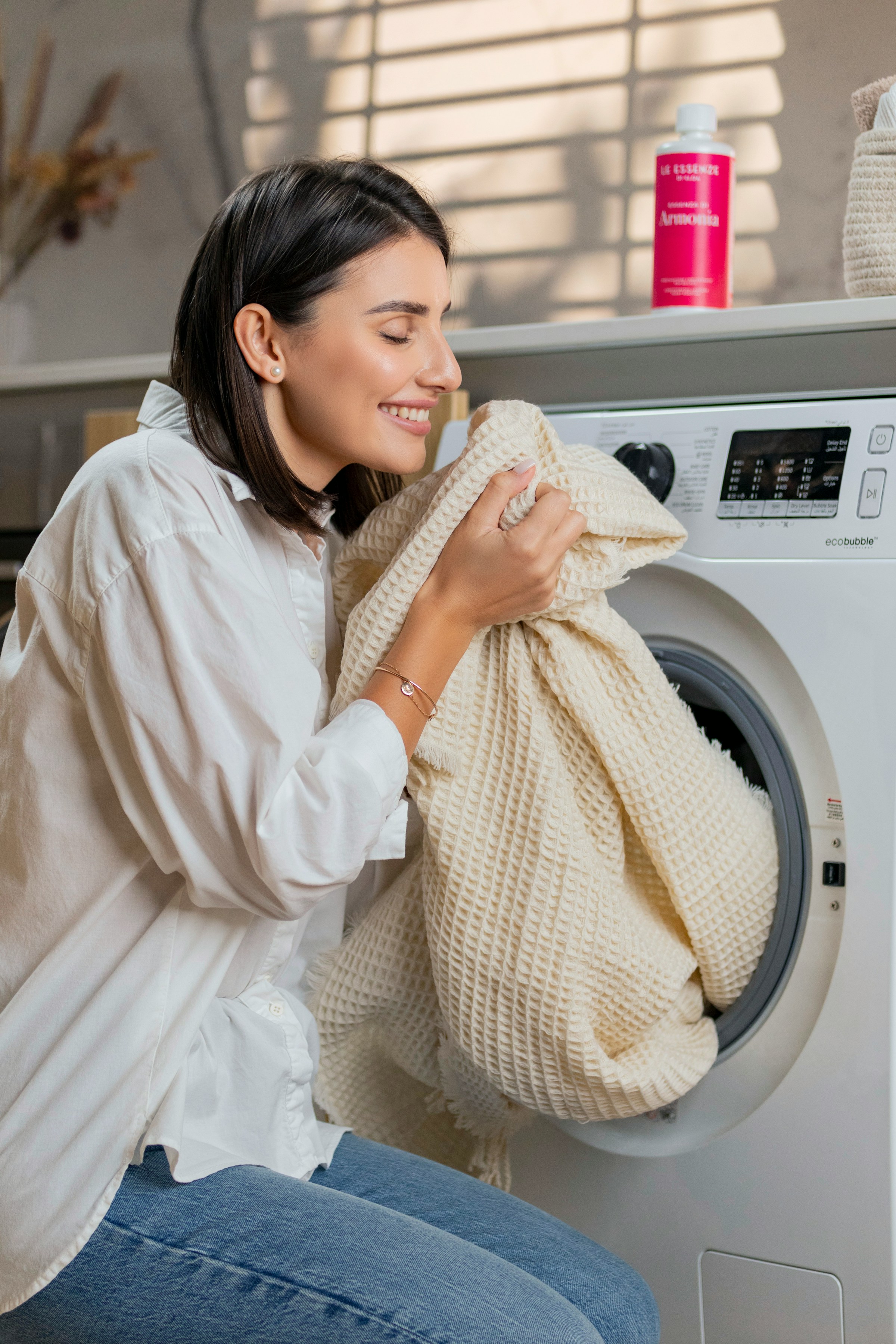 Una mujer sonriente oliendo la ropa lavada | Fuente: Unsplash