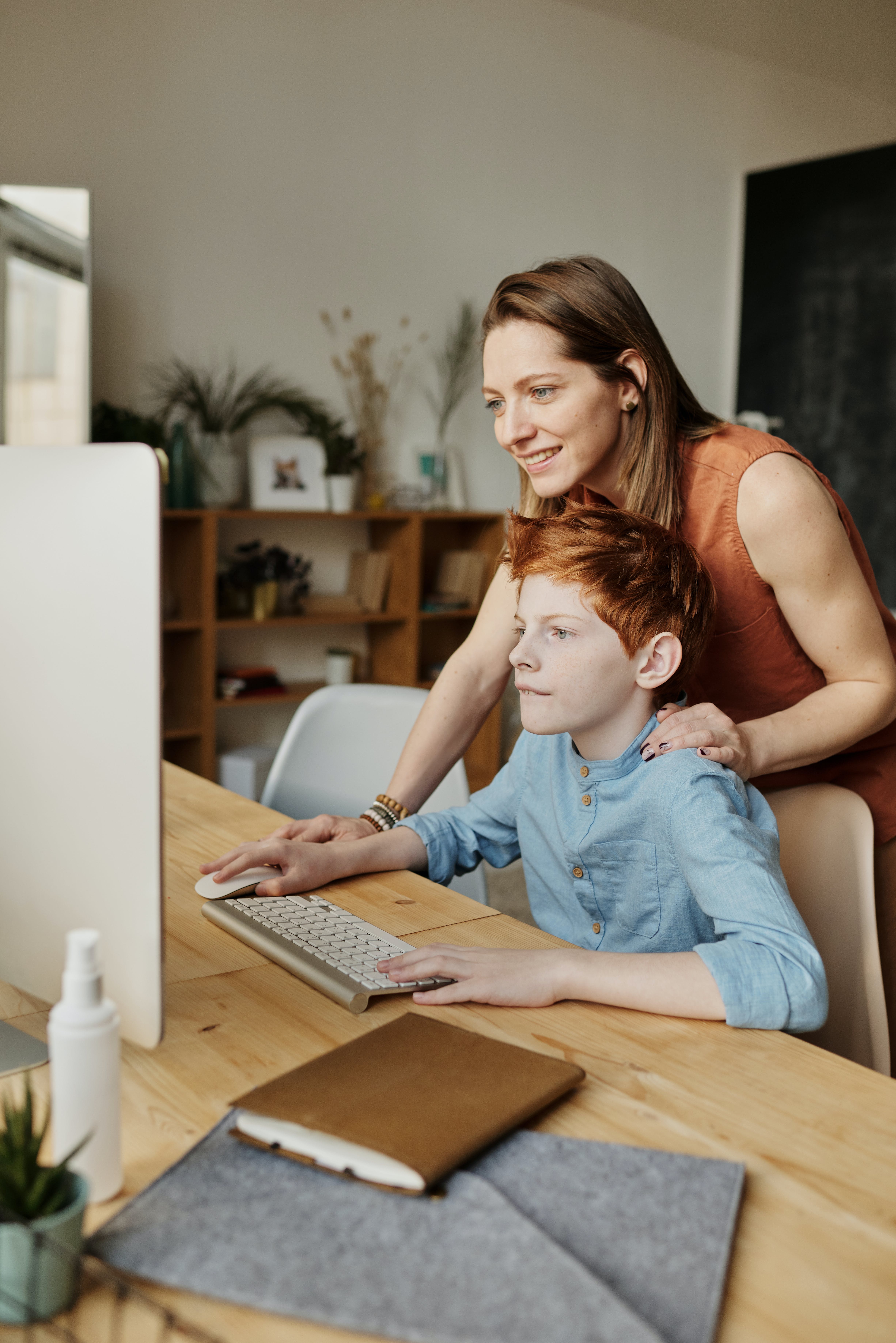 Una mujer se relaciona con un niño mientras utiliza un ordenador personal | Foto: Pexels