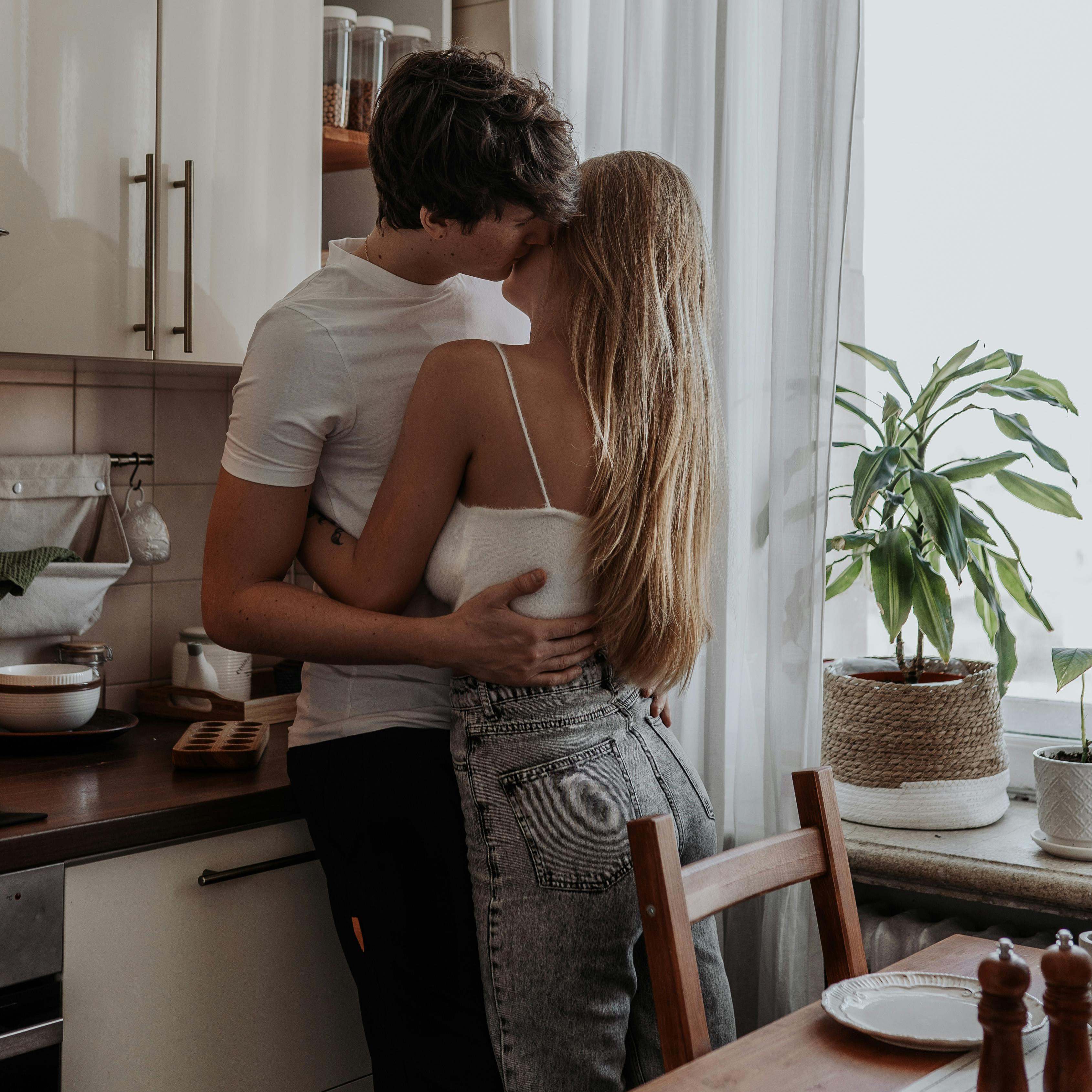 Un hombre abrazando a una mujer en una cocina | Fuente: Pexels