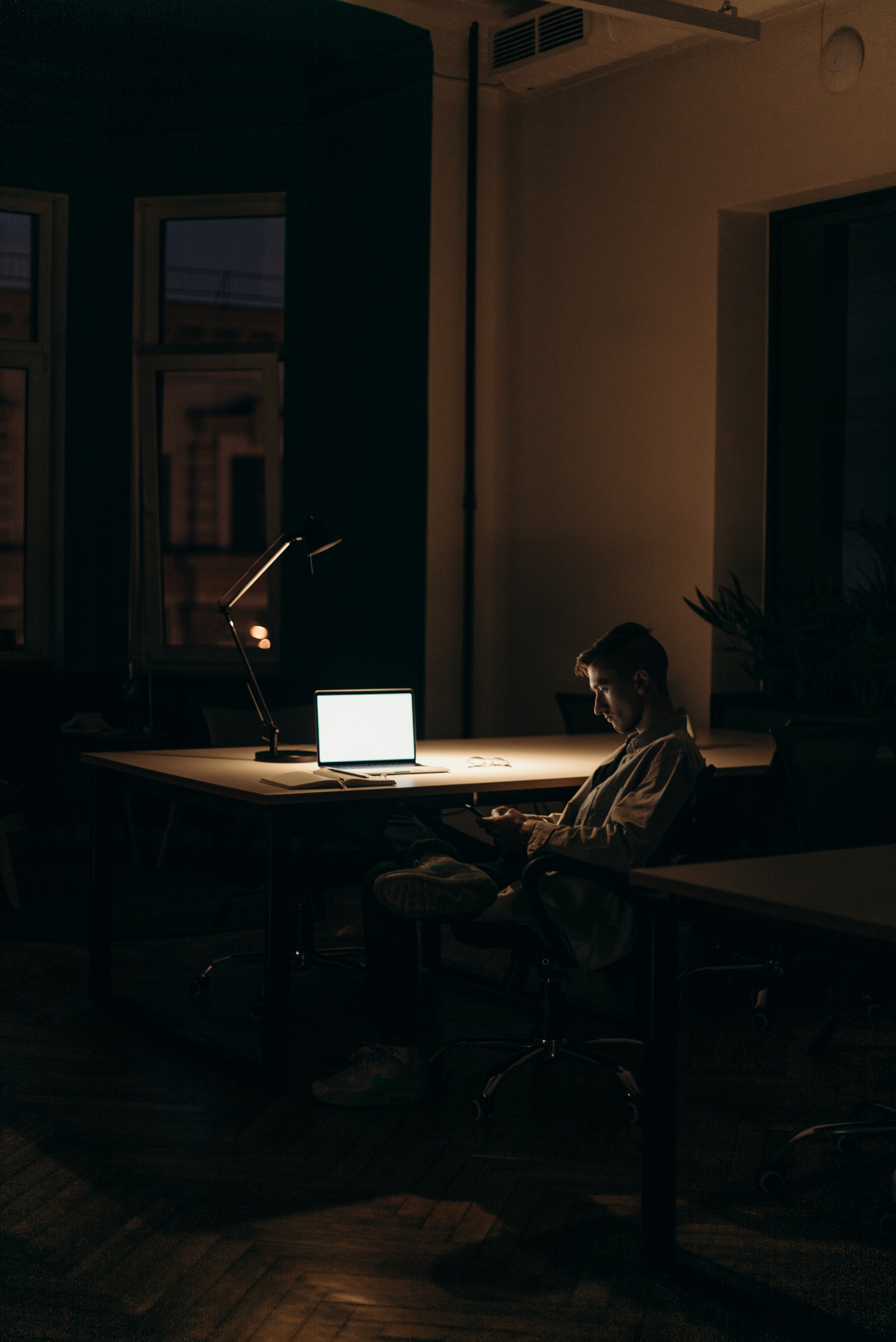 Un hombre sentado frente a una portátil en una habitación oscura. | Foto: Pexels