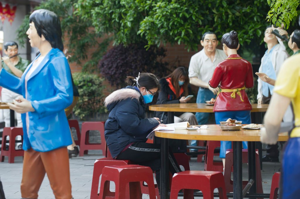 Una niña de Wuhan con su máscara facial leyendo en un café/restaurante al aire libre. I Foto: Getty Images