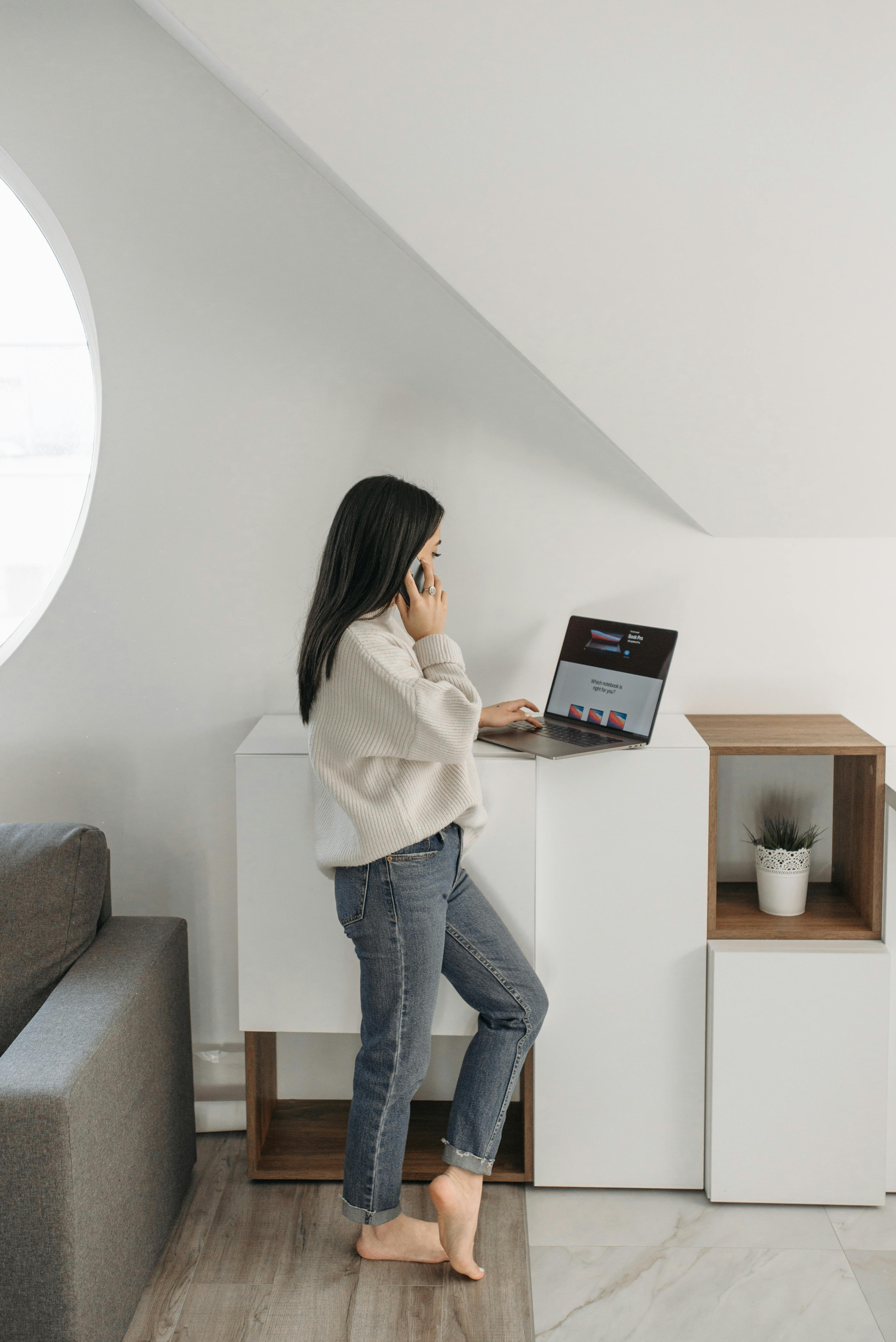 Una mujer hablando por teléfono mientras utiliza un ordenador portátil | Fuente: Pexels