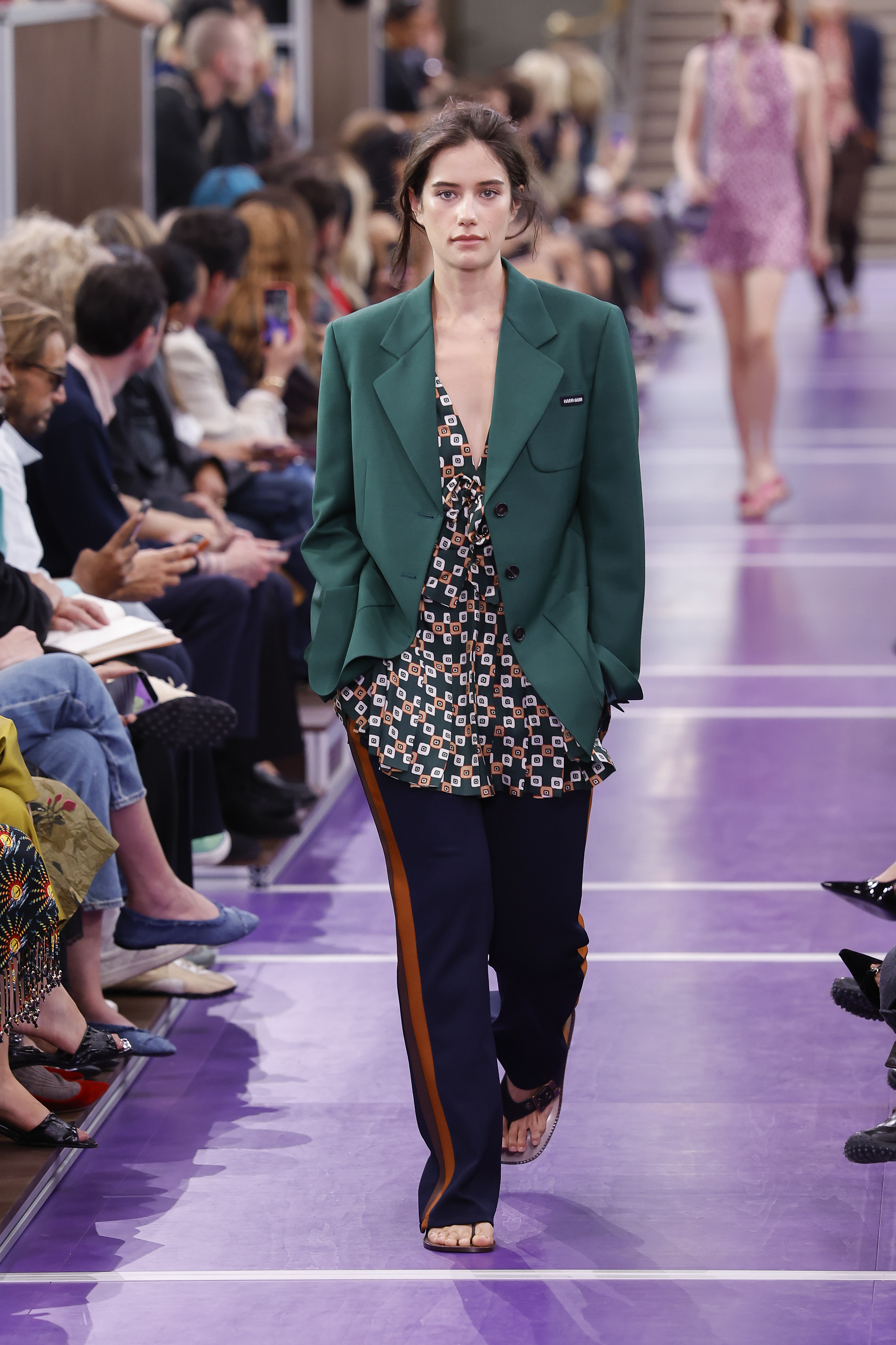 Ella Bleu Travolta da otro paso seguro por la pasarela de Miu Miu, con el público abarrotando a ambos lados de la pasarela morada mientras luce este look llamativo desde otro ángulo. | Fuente: Getty Images