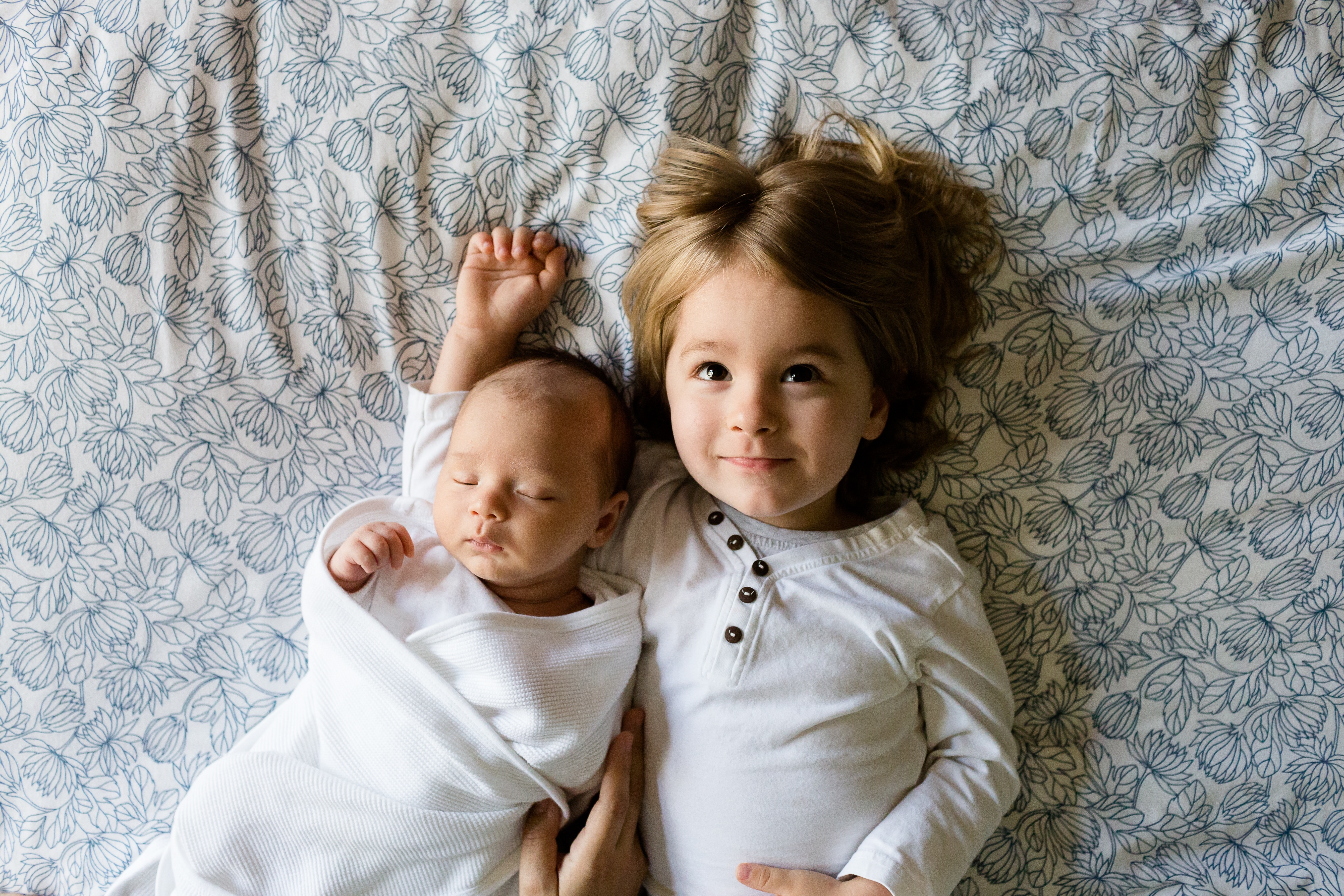 Niña y un bebé acostados en una cama | Fuente: Pexels