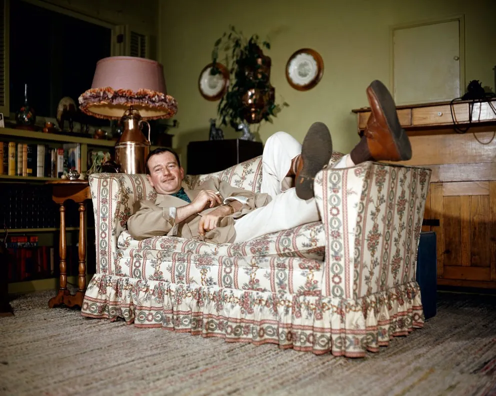 Retrato del actor estadounidense John Wayne (1907 - 1979), mientras se relaja con los pies sobre el brazo de un sofá, en 1950. | Foto: Getty Images