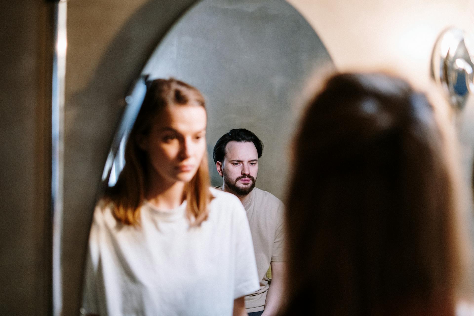 Una mujer mirando el reflejo de su marido en el espejo del baño | Fuente: Pexels