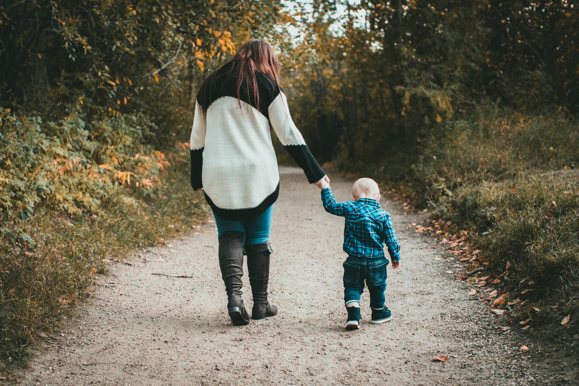 Una mujer coge de la mano a su hijo pequeño mientras caminan juntos | Fuente: Pexels