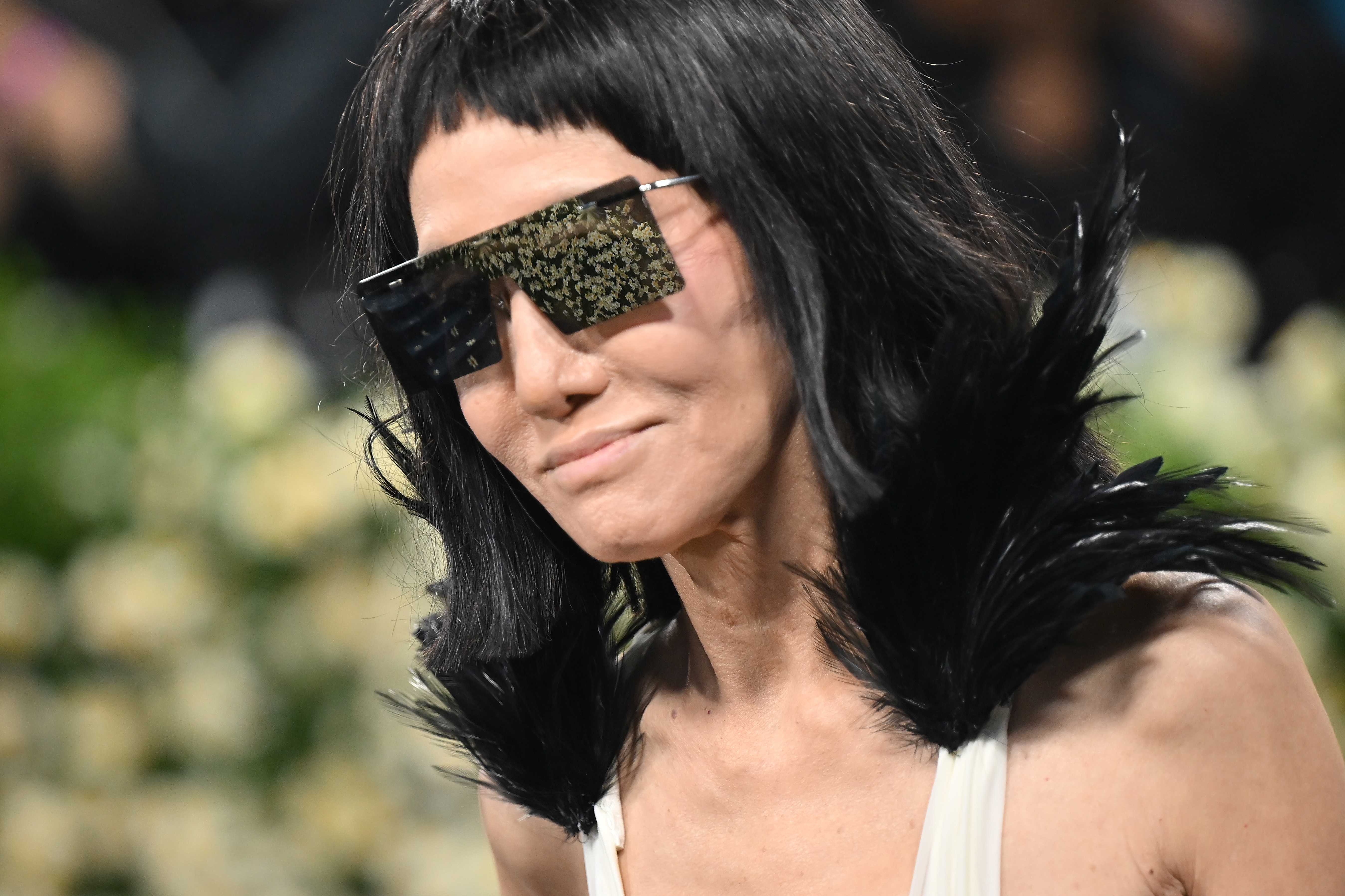 Vera Wang lleva unas gafas de sol reflectantes de gran tamaño y un accesorio de plumas negro azabache a su llegada, lo que permite ver de cerca los atrevidos detalles de su conjunto personalizado.