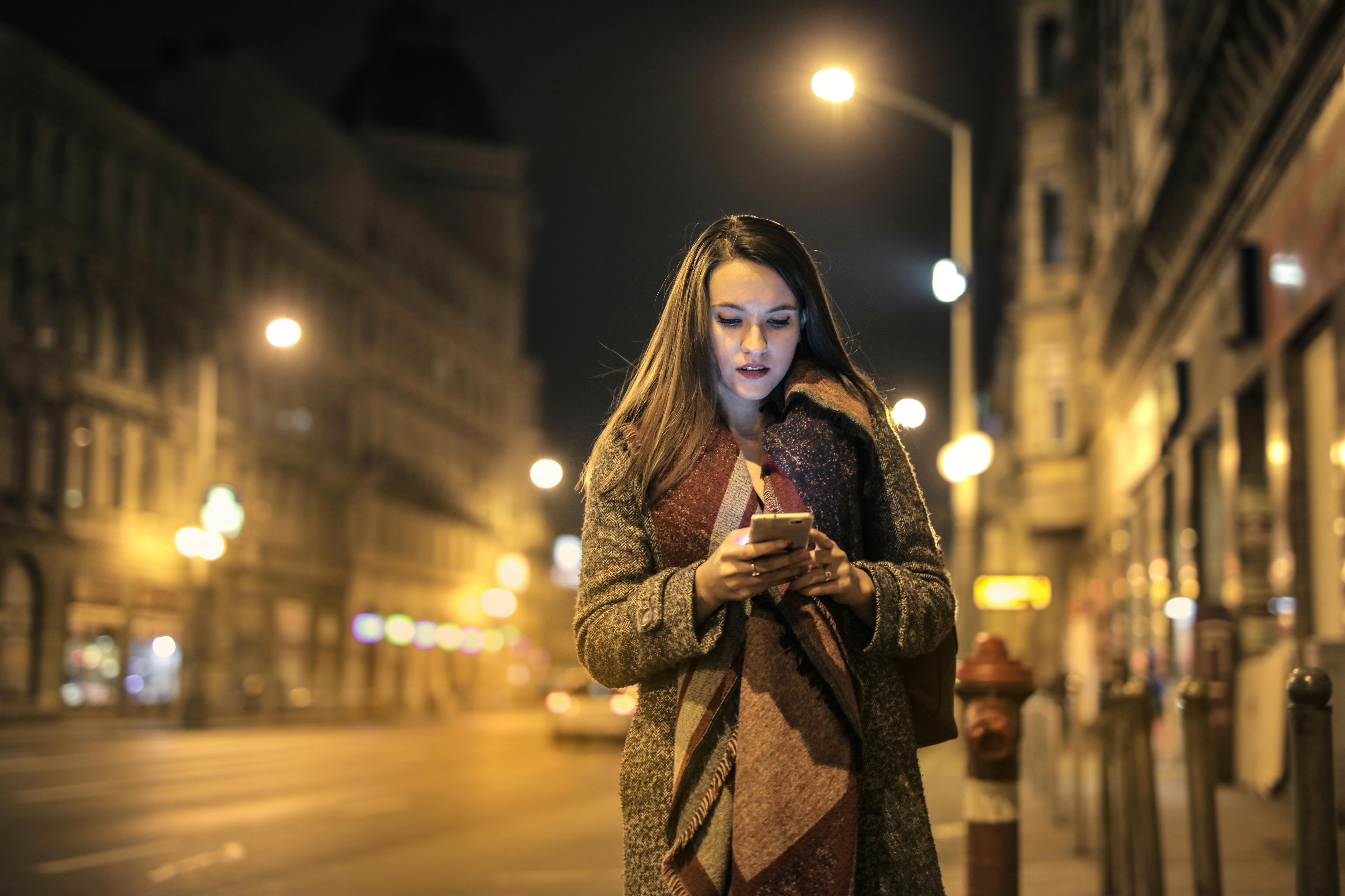 Una mujer haciendo mirando su móvil en medio de una calle | Foto: Pexels