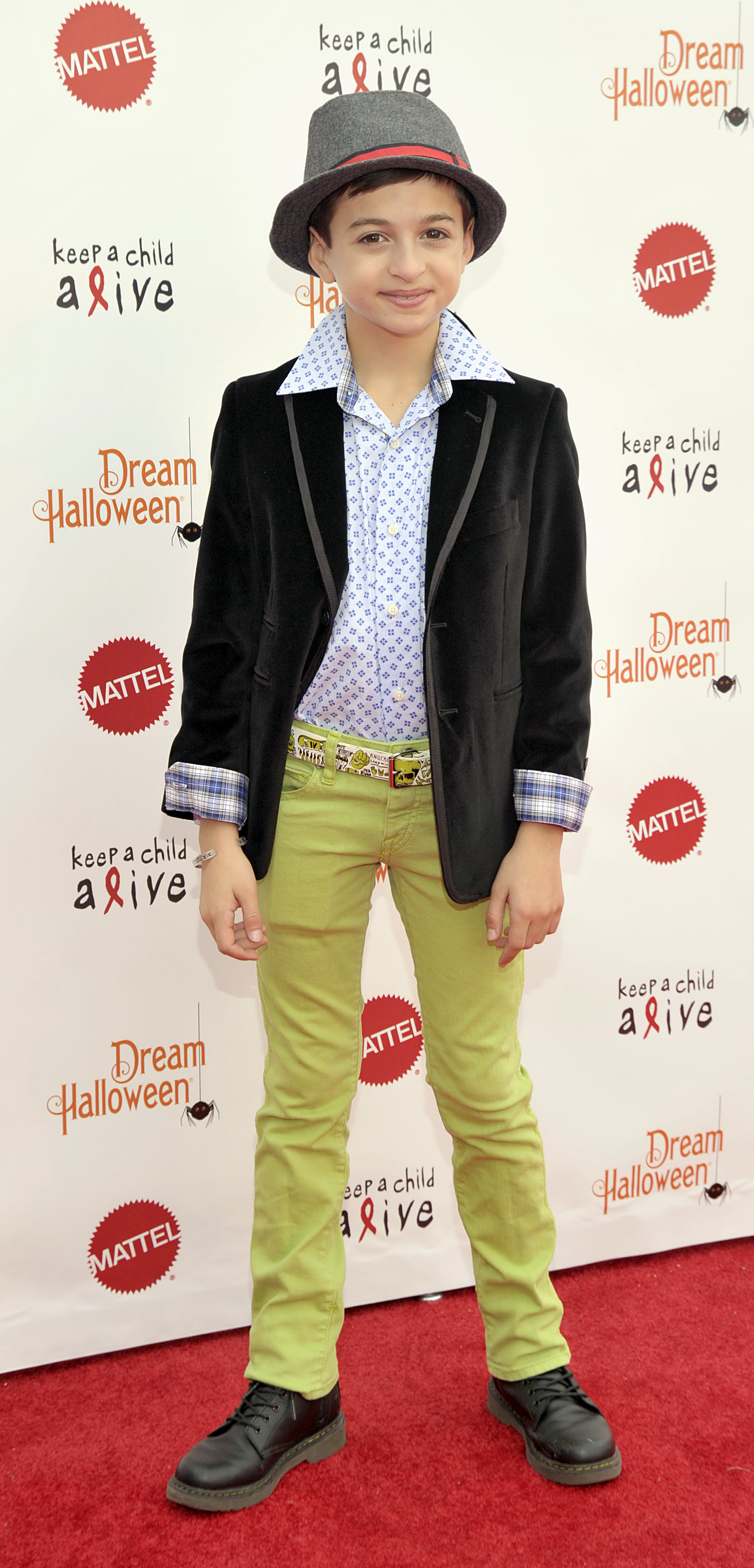 Asiste al 20º evento anual "Dream Halloween" de Keep a Child Alive, celebrado en el Barker Hangar de Santa Mónica, California, con un sombrero fedora gris, una chaqueta negra, una camisa azul estampada, unos pantalones de color verde brillante y unas botas negras. | Fuente: Getty Images