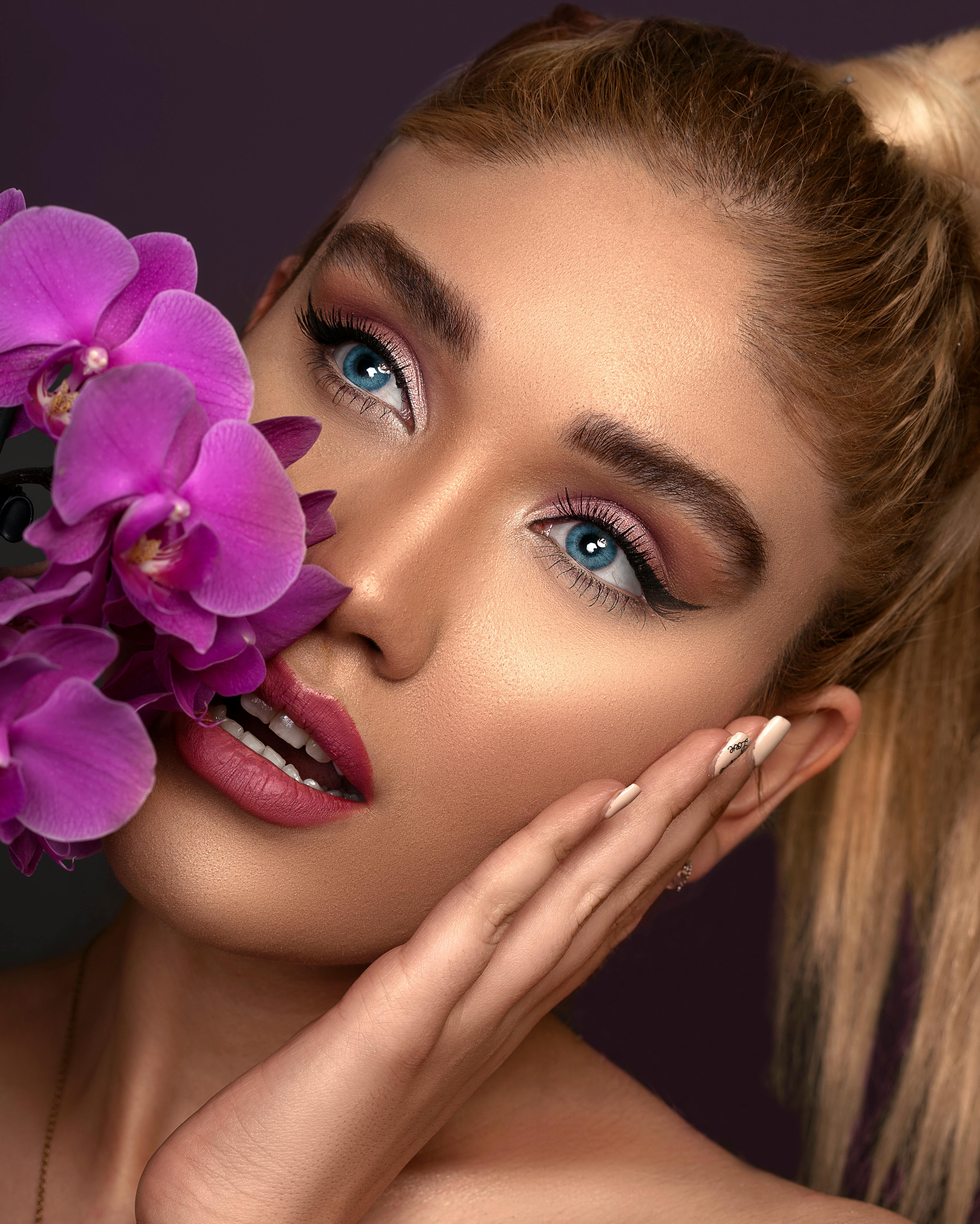 Una mujer posando con orquídeas rosas | Fuente: Pexels