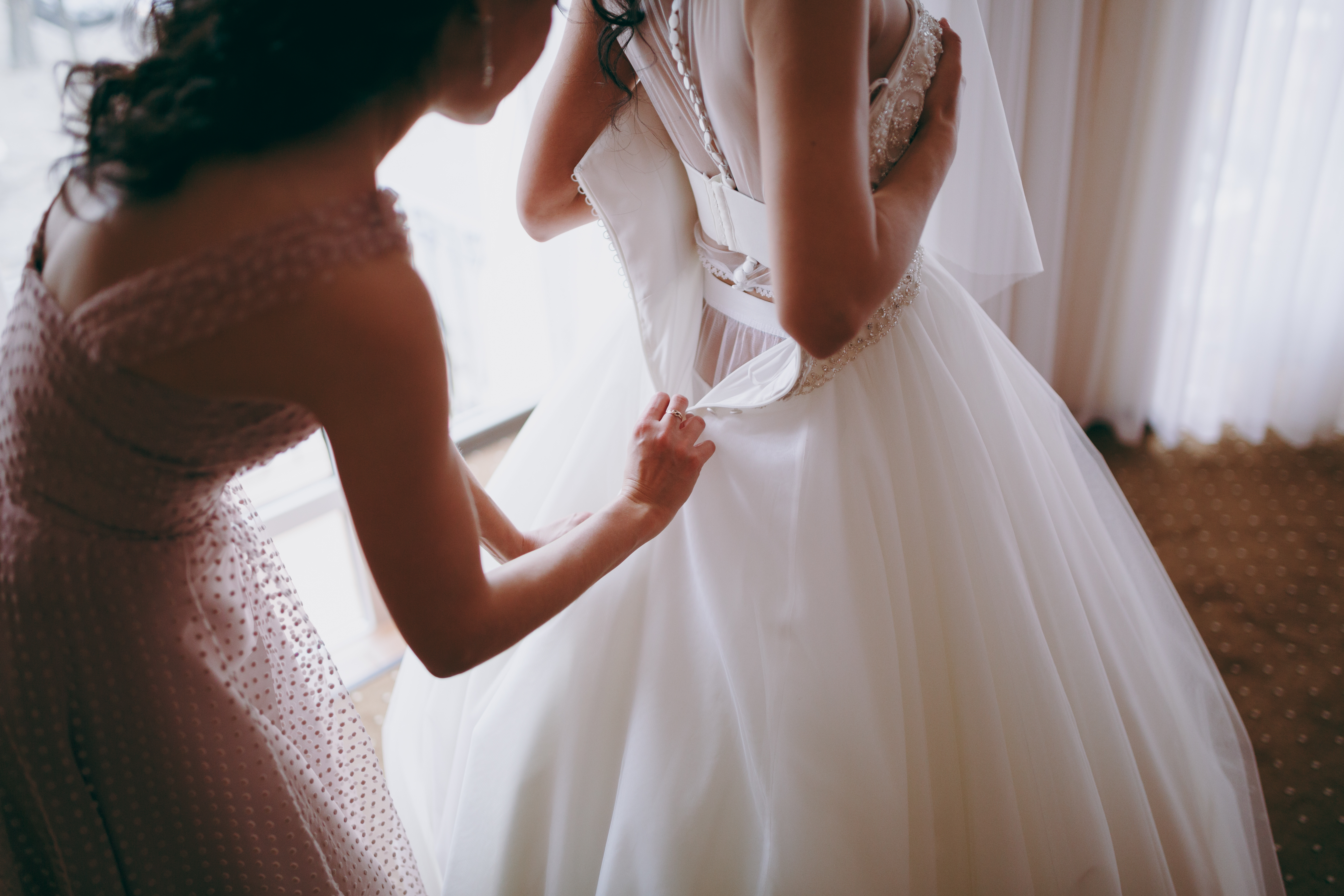 Una mujer ayuda a una novia a ponerse el vestido de novia. | Foto: Shutterstock