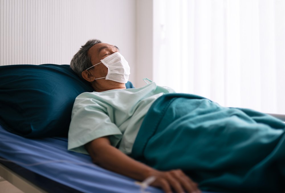 Paciente mayor acostado en una cama de hospital usando mascarilla. I Foto: Shutterstock