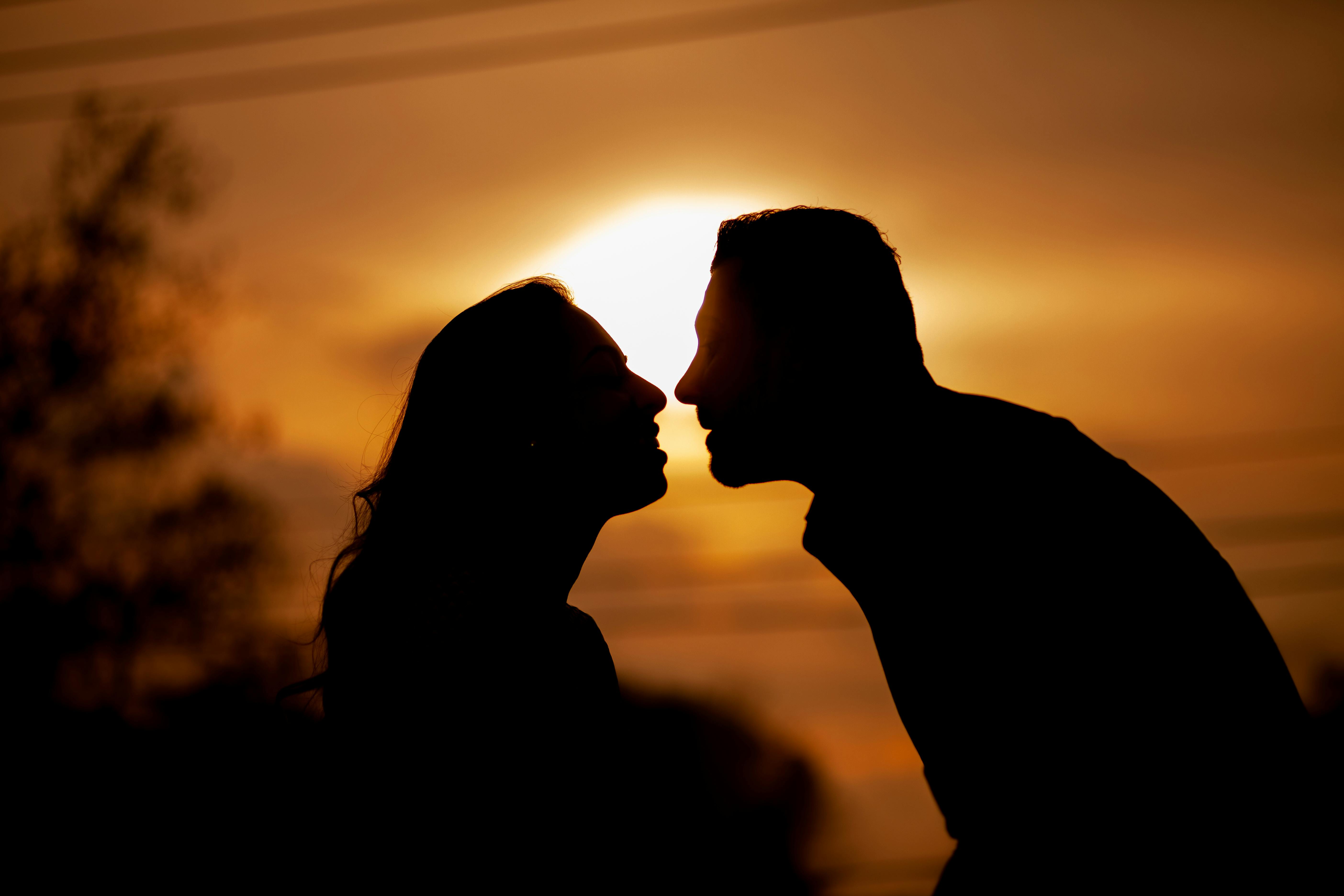 Silueta de una pareja feliz disfrutando de la puesta de sol | Fuente: Pexels