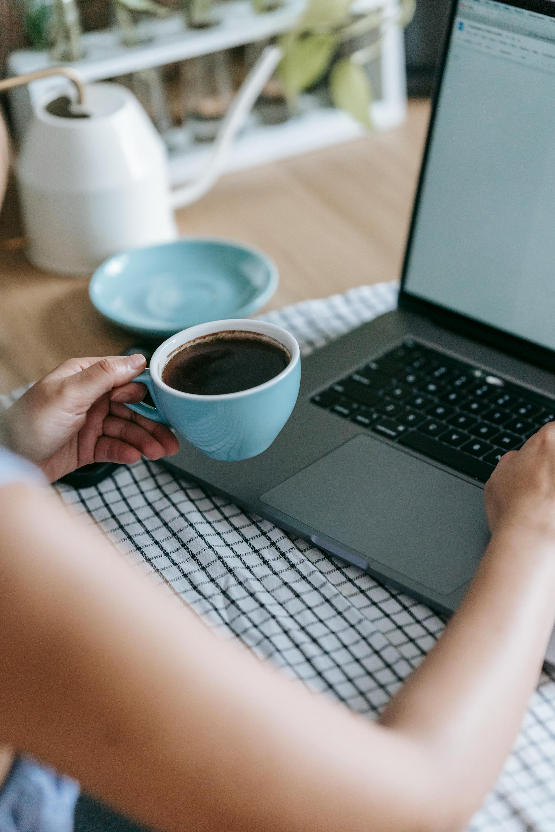 Una mujer con una taza de café en la mano mientras usa su portátil | Fuente: Pexels