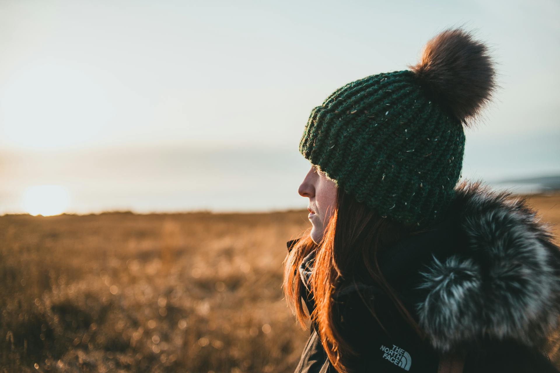 Primer plano de una mujer admirando la naturaleza en una orilla cubierta de hierba al atardecer | Fuente: Pexels