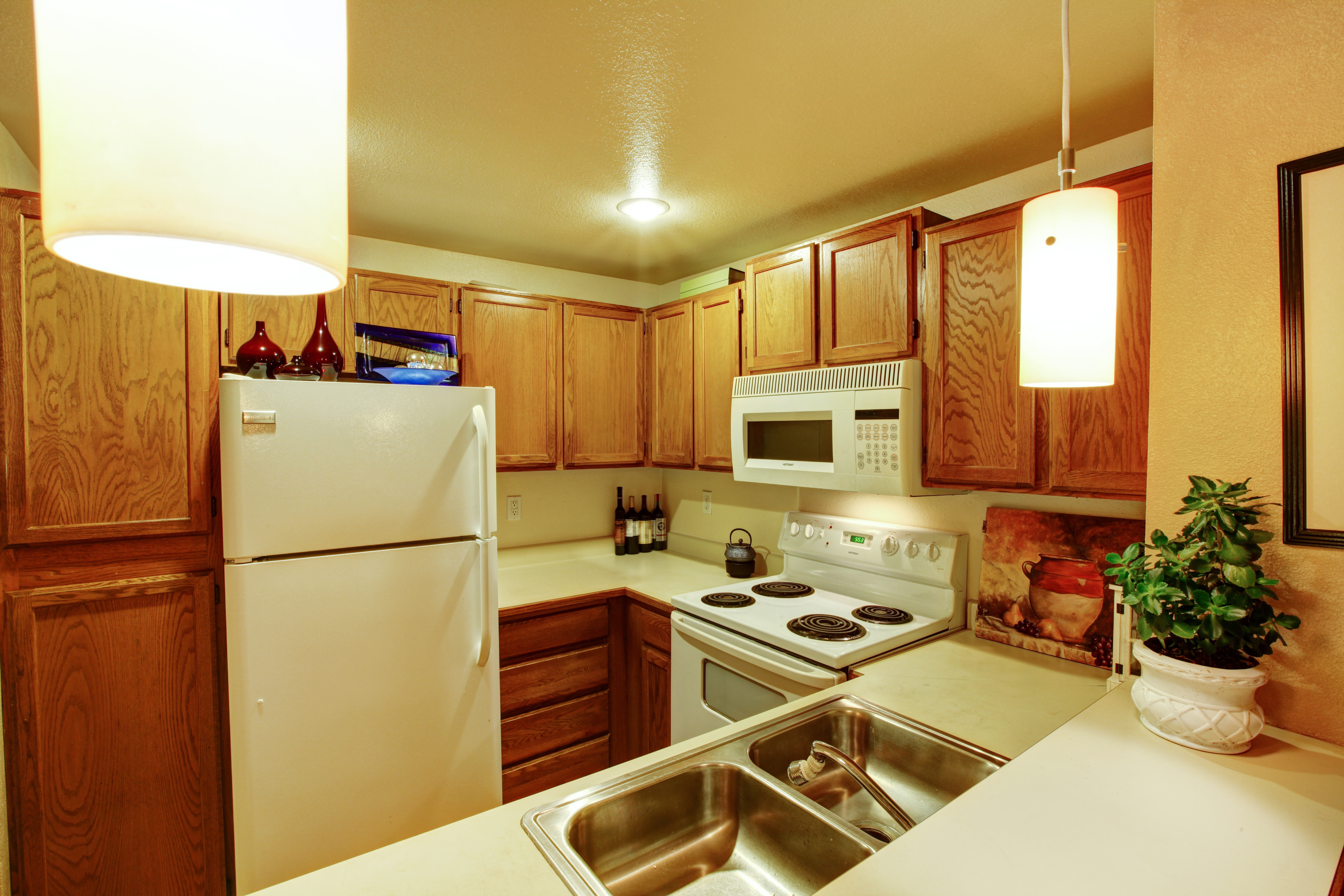 Vista de armarios de cocina con fregadero y electrodomésticos blancos antiguos | Fuente: Shutterstock