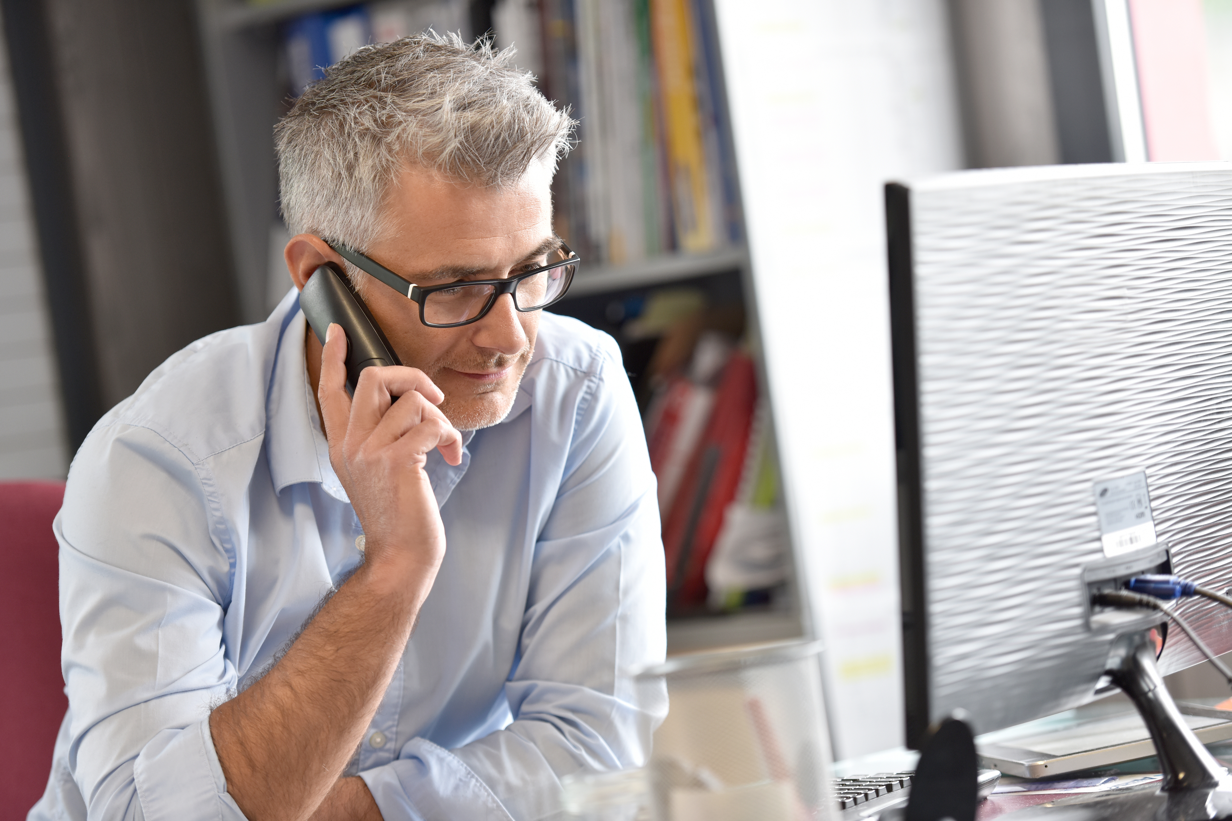 Hombre de negocios en la oficina hablando por teléfono. | Fuente: Shutterstock