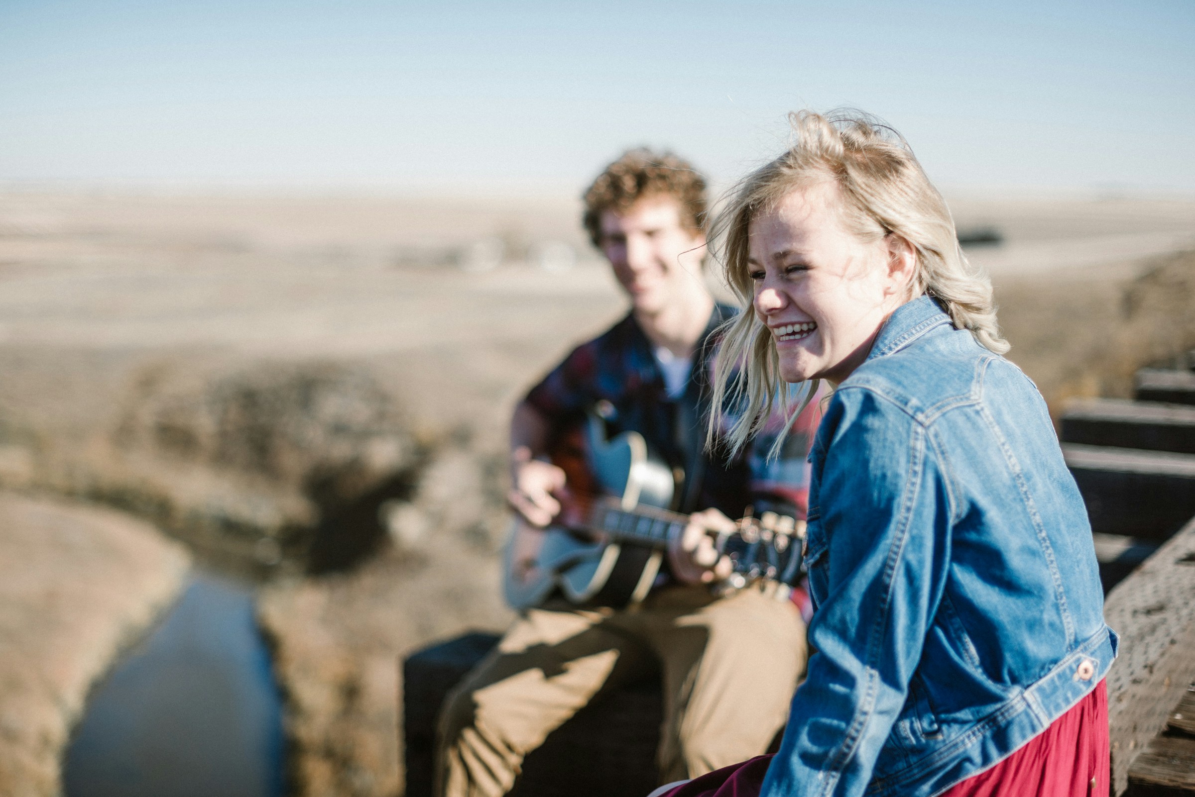 Una mujer sonríe sentada junto a un hombre que toca la guitarra | Fuente: Unsplash