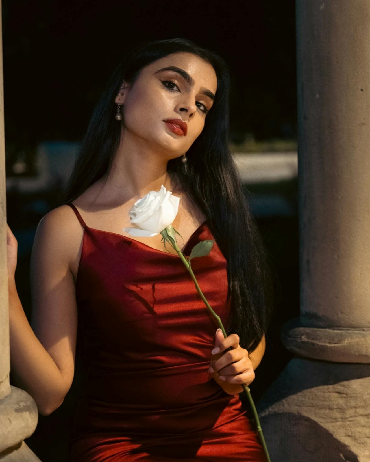 Una mujer con un vestido rojo sosteniendo una rosa | Fuente: Pexels