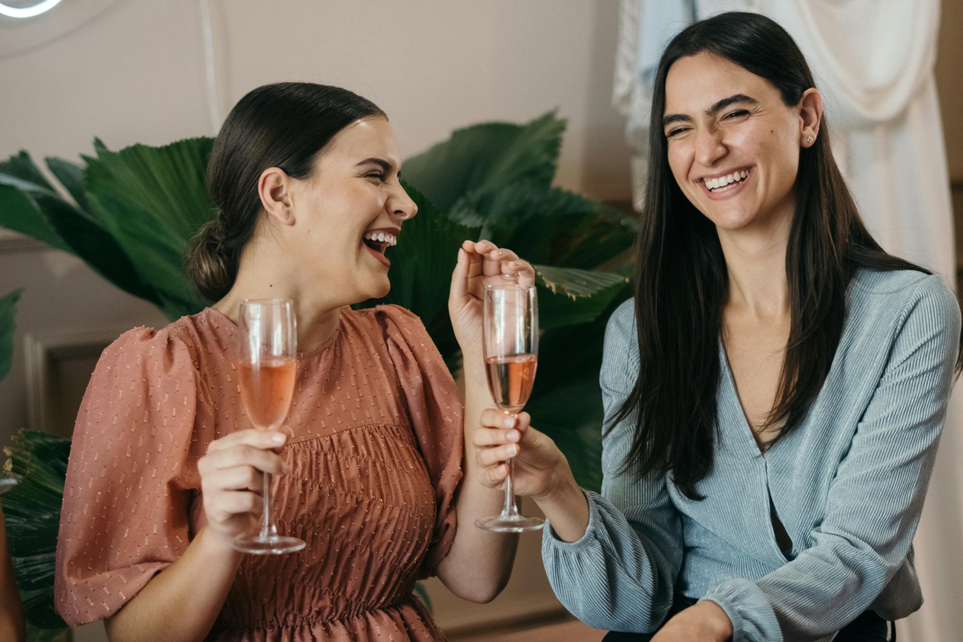 Dos mujeres riendo mientras sostienen bebidas en una fiesta | Fuente: Pexels