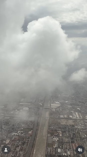 Desde la ventanilla de un avión se ven unas densas nubes de tormenta que se ciernen sobre las extensas redes urbanísticas y las autopistas el 11 de octubre de 2026. Unas imponentes masas de cúmulos llenan el cielo, ocultando parcialmente el paisaje urbano que se ve desde arriba durante el vuelo. | Fuente: Instagram/selmablair