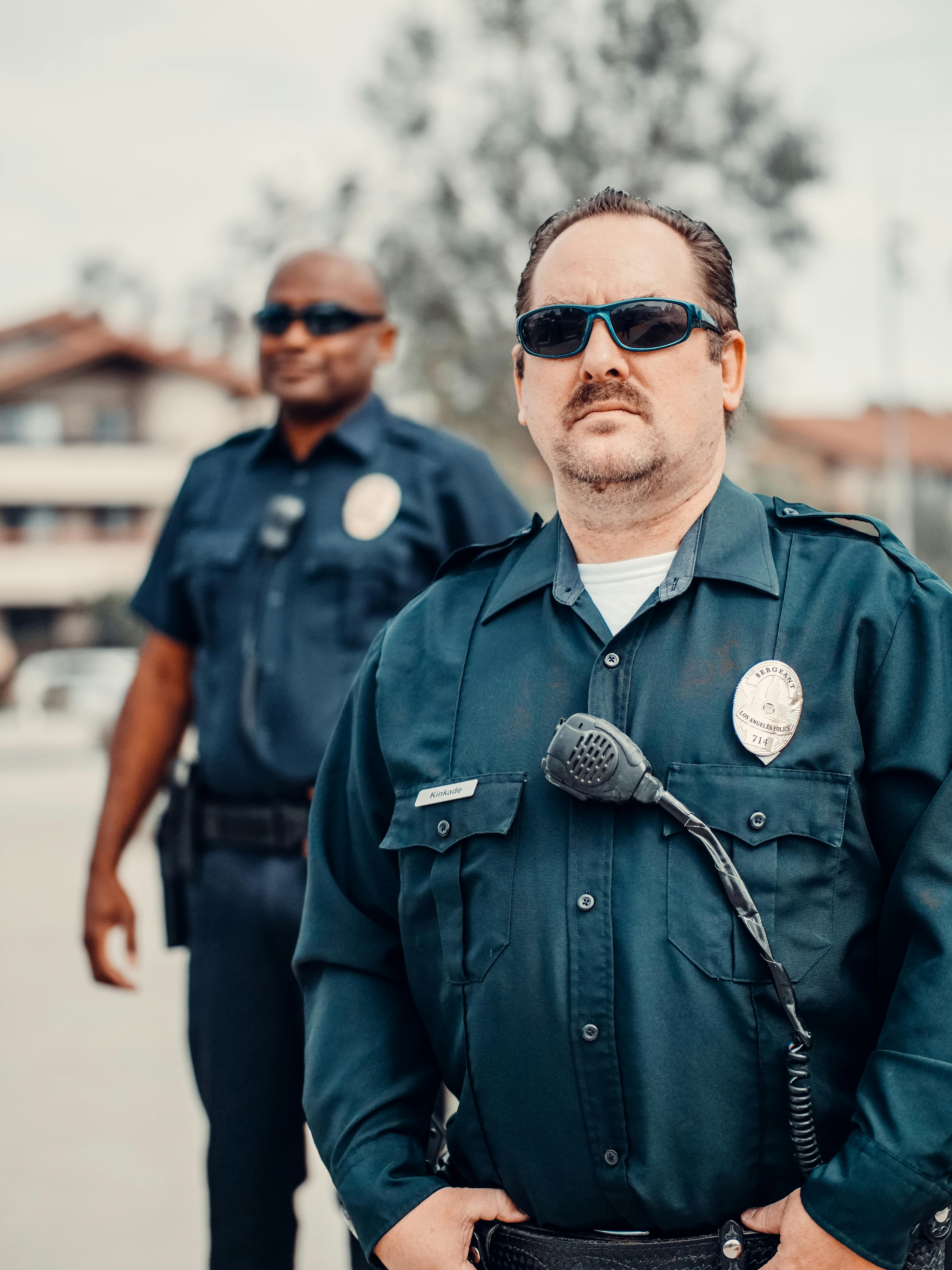Un policía de aspecto sombrío detrás de un compañero | Fuente: Pexels