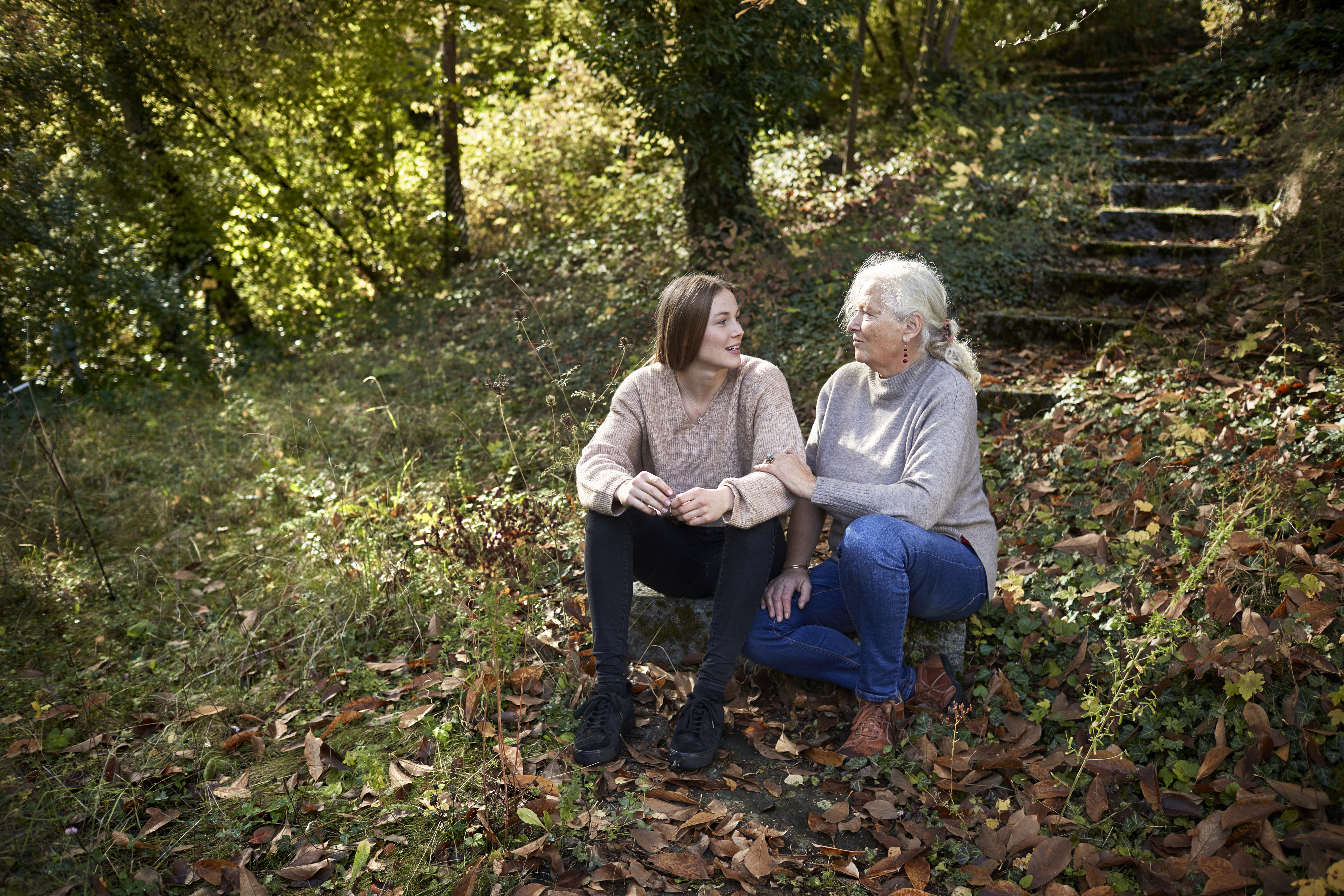 Abuela y nieta adulta sentadas en un jardín otoñal | Foto: Getty Images