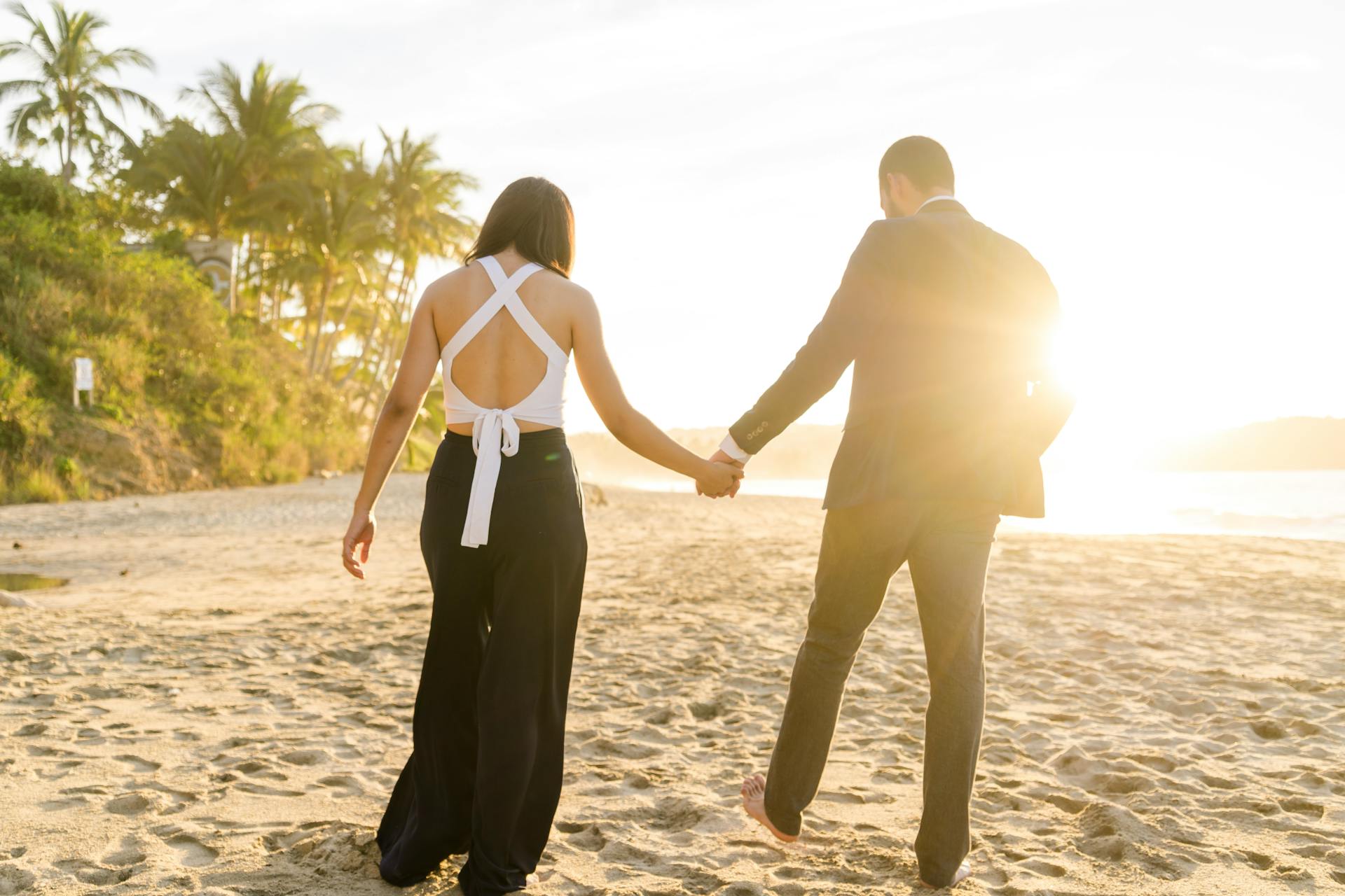 Vista trasera de una pareja paseando por la playa | Fuente: Pexels