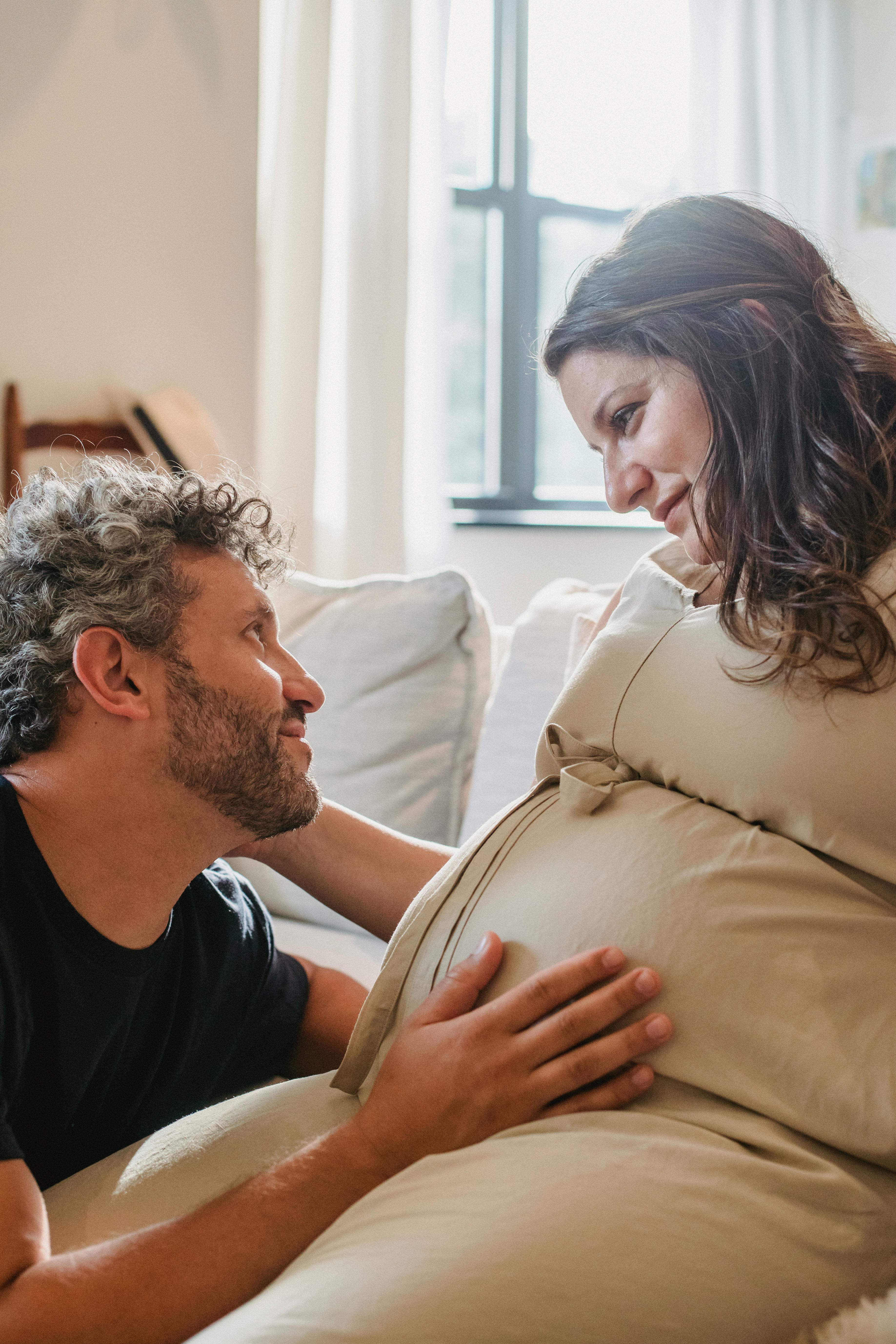 Hombre tocando el vientre de su mujer embarazada mientras se miran fijamente | Fuente: Pexels
