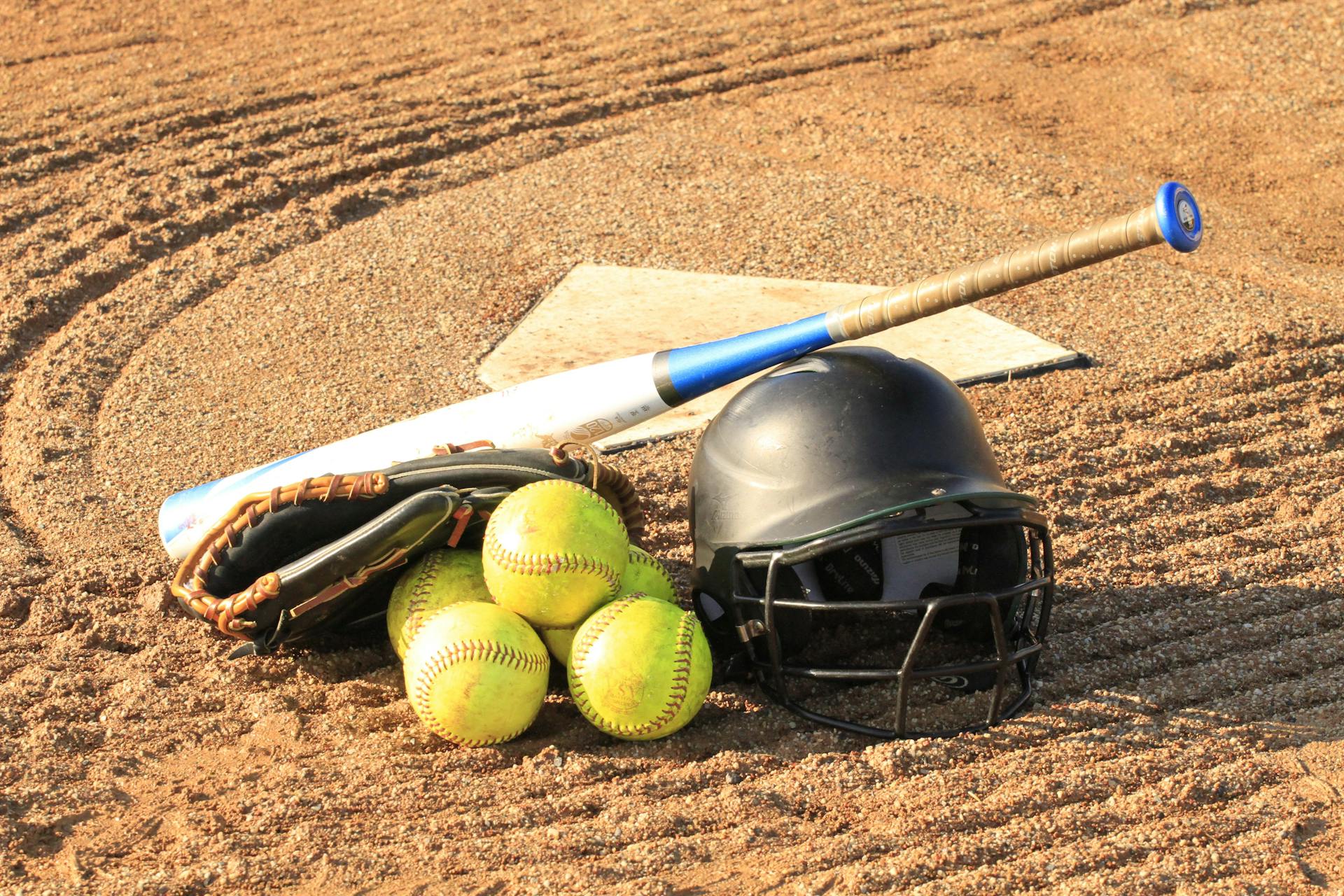 Un bate de béisbol con un casco y pelotas | Fuente: Pexels