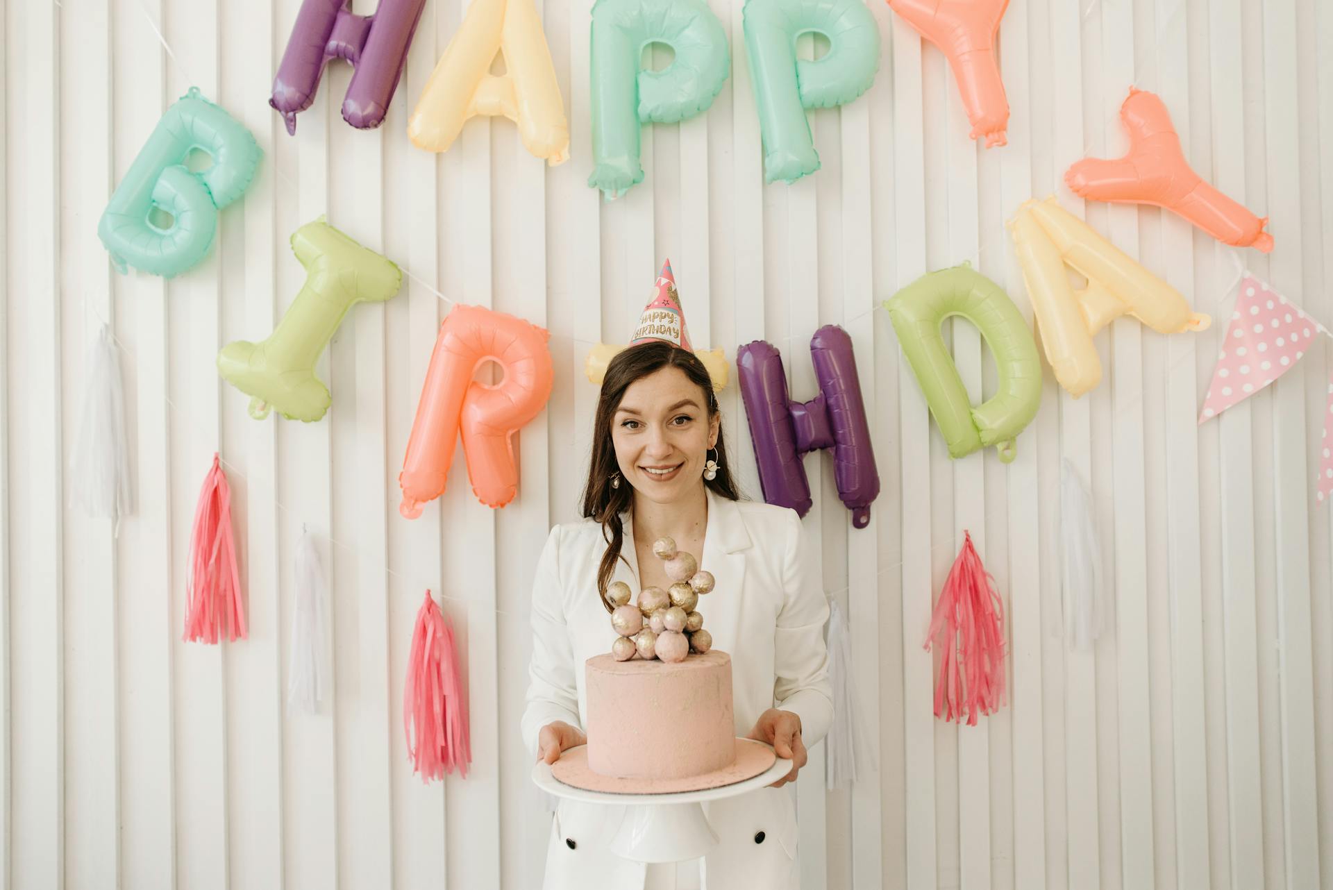 Una mujer sostiene un Pastel y lleva un sombrero de fiesta | Fuente: Pexels