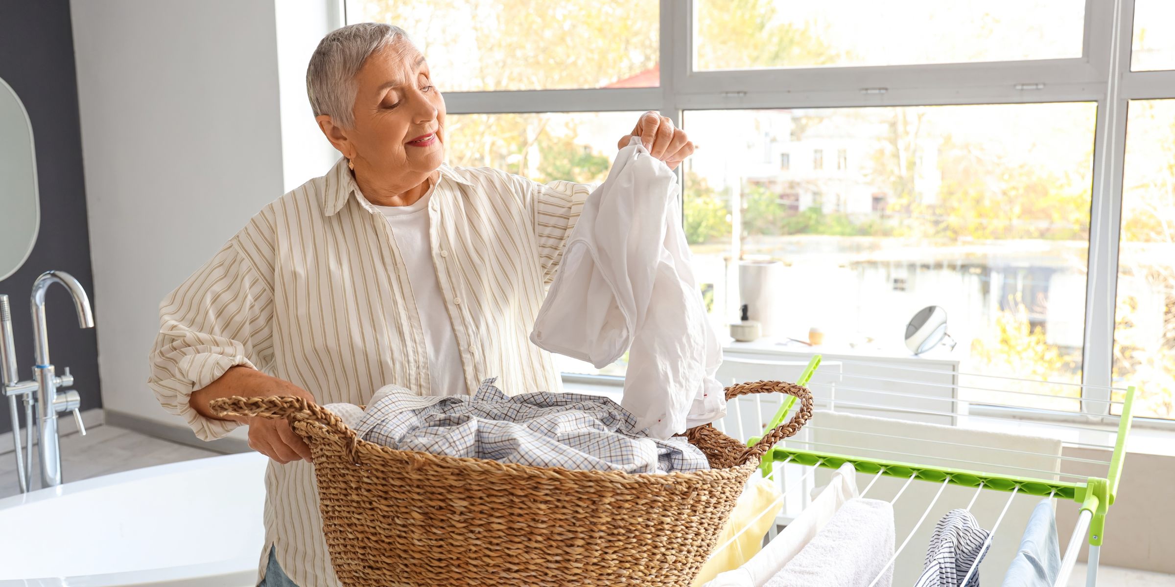 Una mujer mayor con una cesta de la ropa en casa | Fuente: Shutterstock